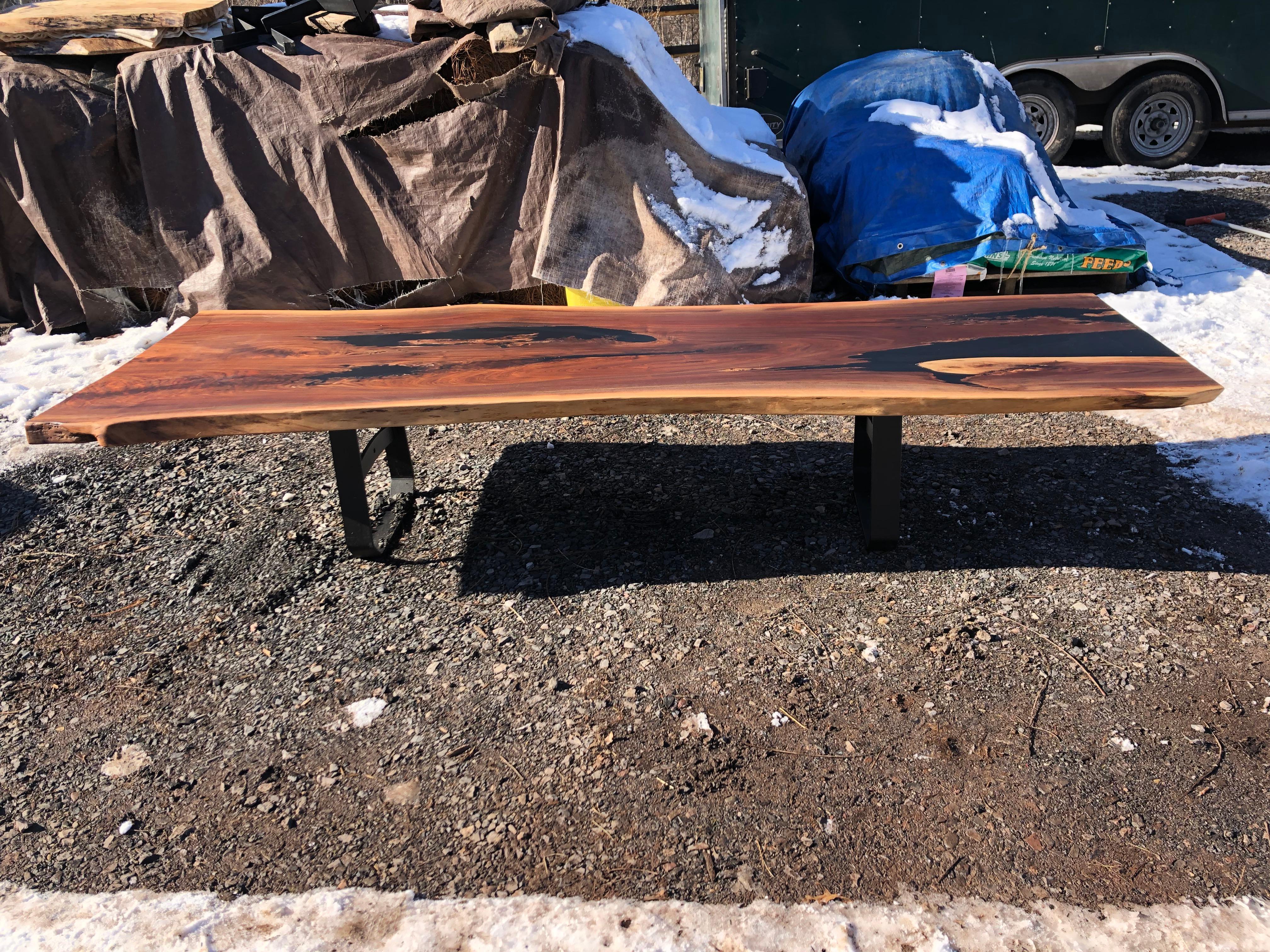 Very long live edge walnut slab coffee table having gorgeous rectangular irregular shape, lively grain with amazing coloration, and some black resin filled crevices. Legs are black iron in a contemporary industrial design. Because the slab is