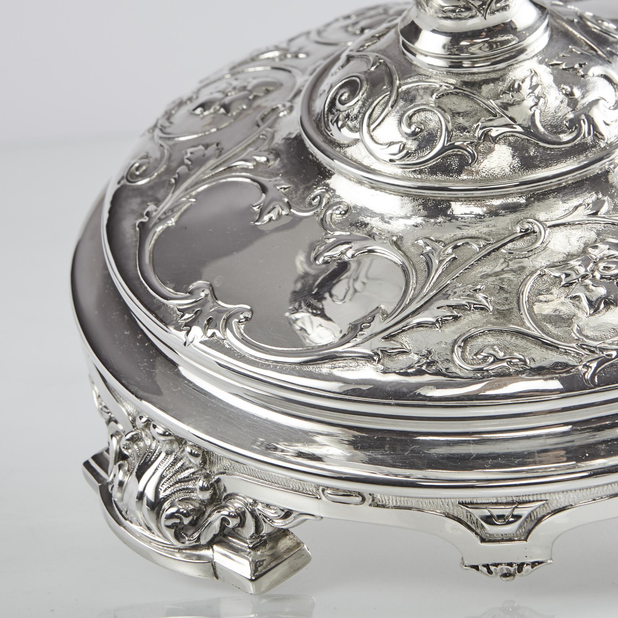 A stunning antique silver bowl or jardinière, based on a classical style with a round pedestal base and oval boat-shaped dish. It is hand-chased with bas-relief entwined leaf and flower decoration and has two scrolling handles cast as stylized