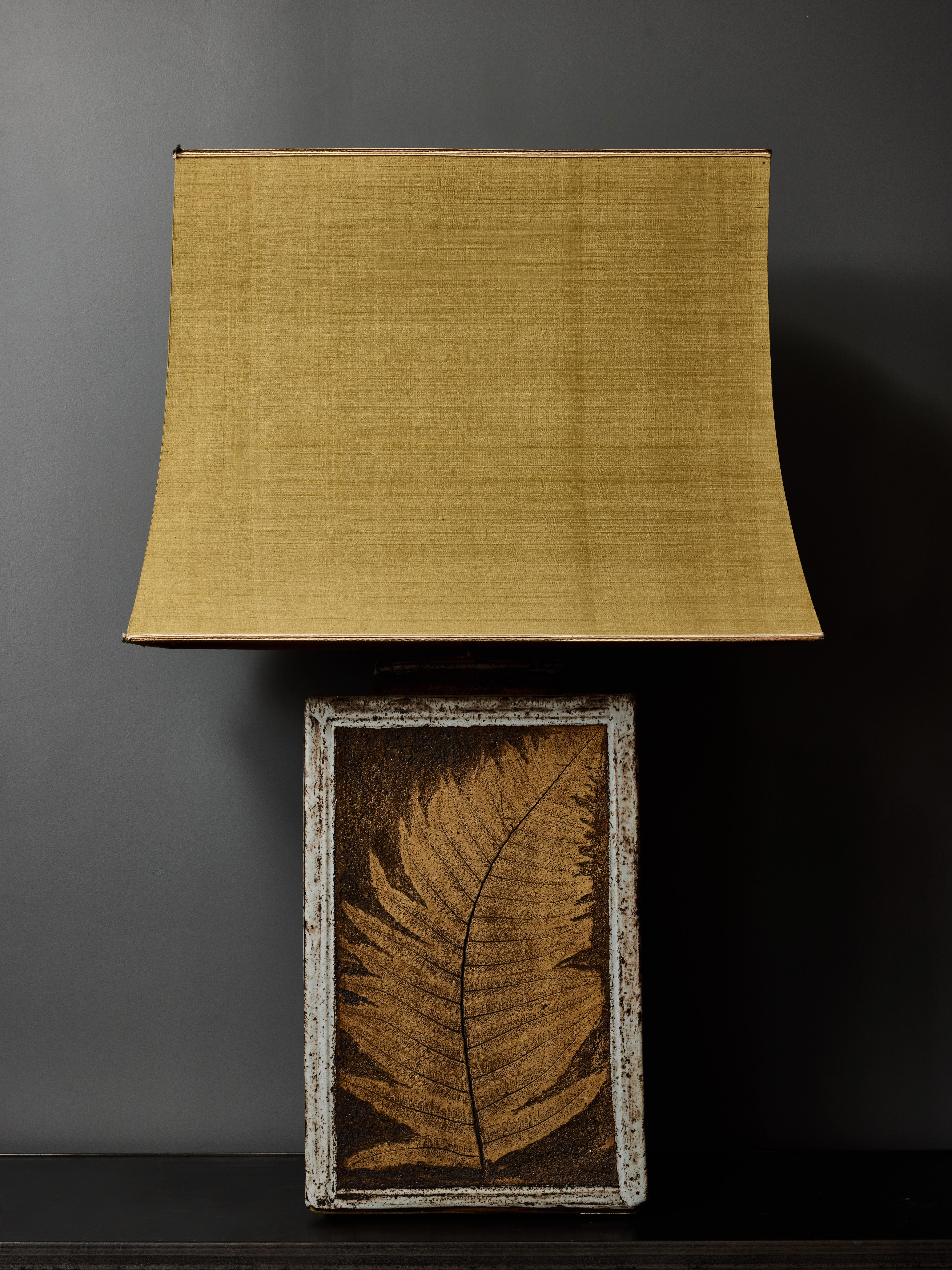 Cette grande lampe de table rectangulaire en céramique présente un design inspiré des herbiers, mettant en évidence une feuille naturelle magnifiquement gravée, mise en valeur par les trois émaux de la pièce.

Dimensions sans les abat-jour : 30 x 15