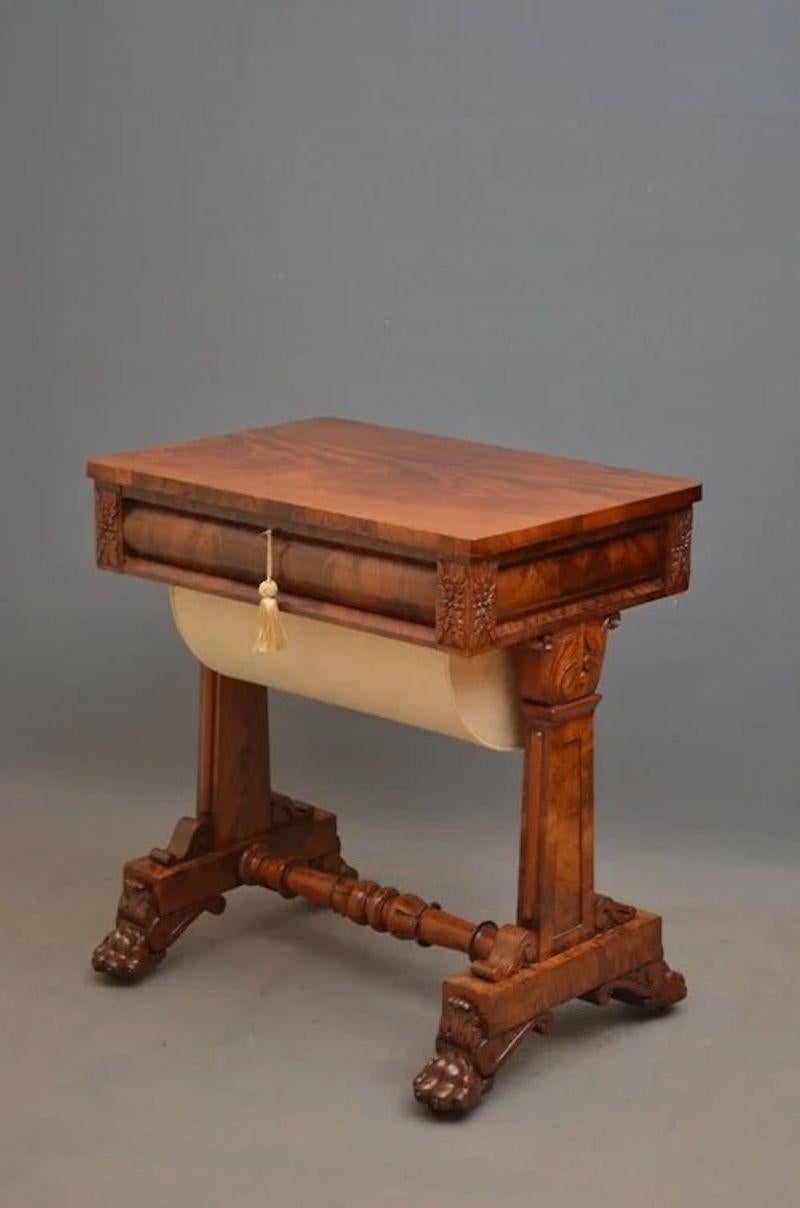 An impressive William IV work table in mahogany, having flamed mahogany top with cylindrical frieze drawer fitted with small compartments and silk basket below, all raised on crisply carved supports terminating in carved paw feet united by turned