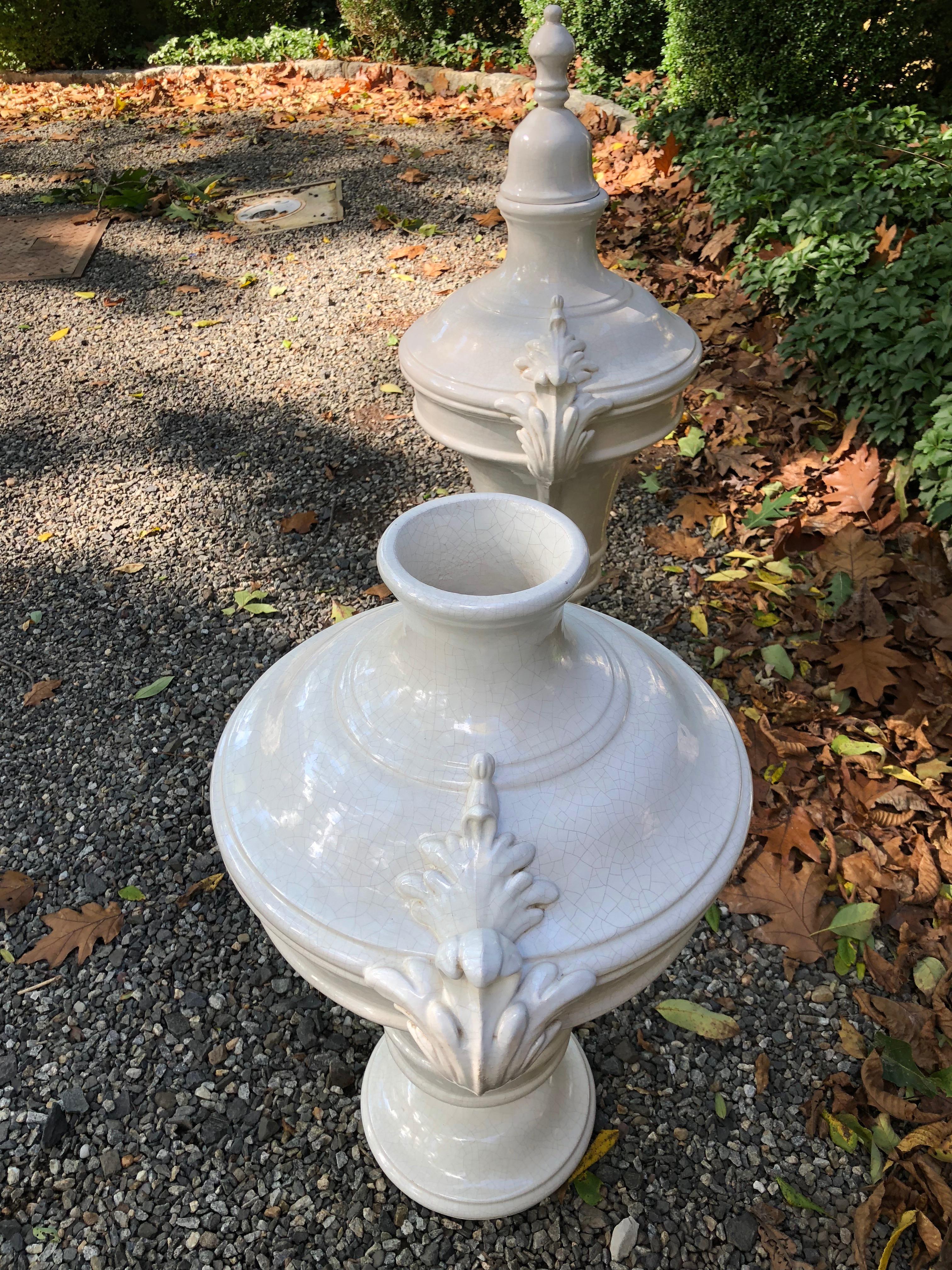 Pair of monumental neoclassical style lidded urns with removable lids and sculptural handles. Marked Italy on underside.
 