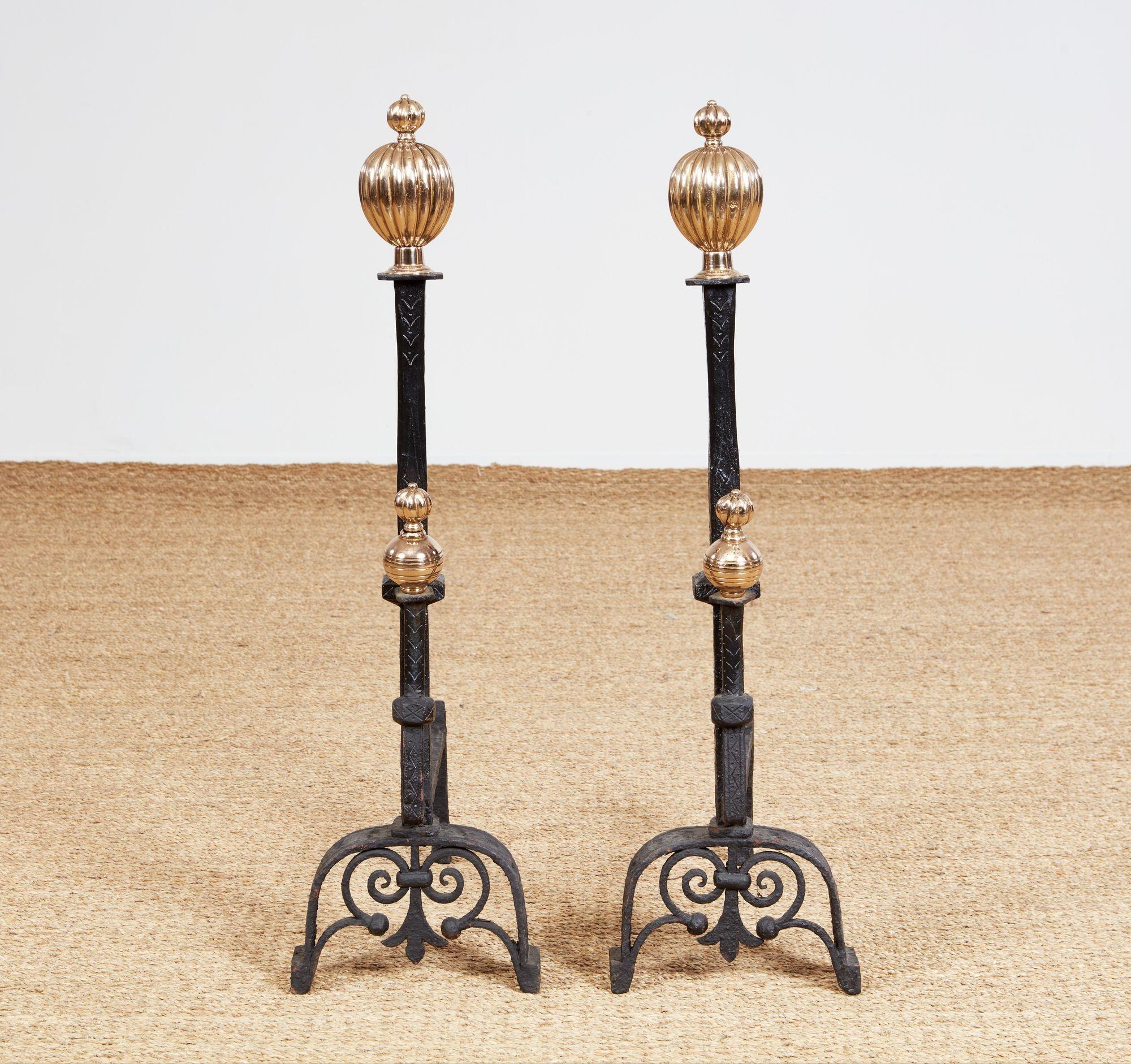 A large scale pair of early hand-forged andirons in black wrought iron with contrasting brass finials to tops and to spit supports. Fabulous decorative detail to arched legs and under scrolls, as well as to square section chased shaft and striated