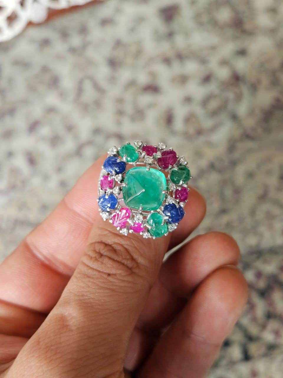 A very gorgeous & beautiful, one of a kind, Tutti Frutti style, Emerald, Blue Sapphire & Ruby Cocktail / Dome Ring set in 18K White Gold & Diamonds. The weight of the Emerald sugarloaf is 6.09 carats. The Emerald is completely natural, without any