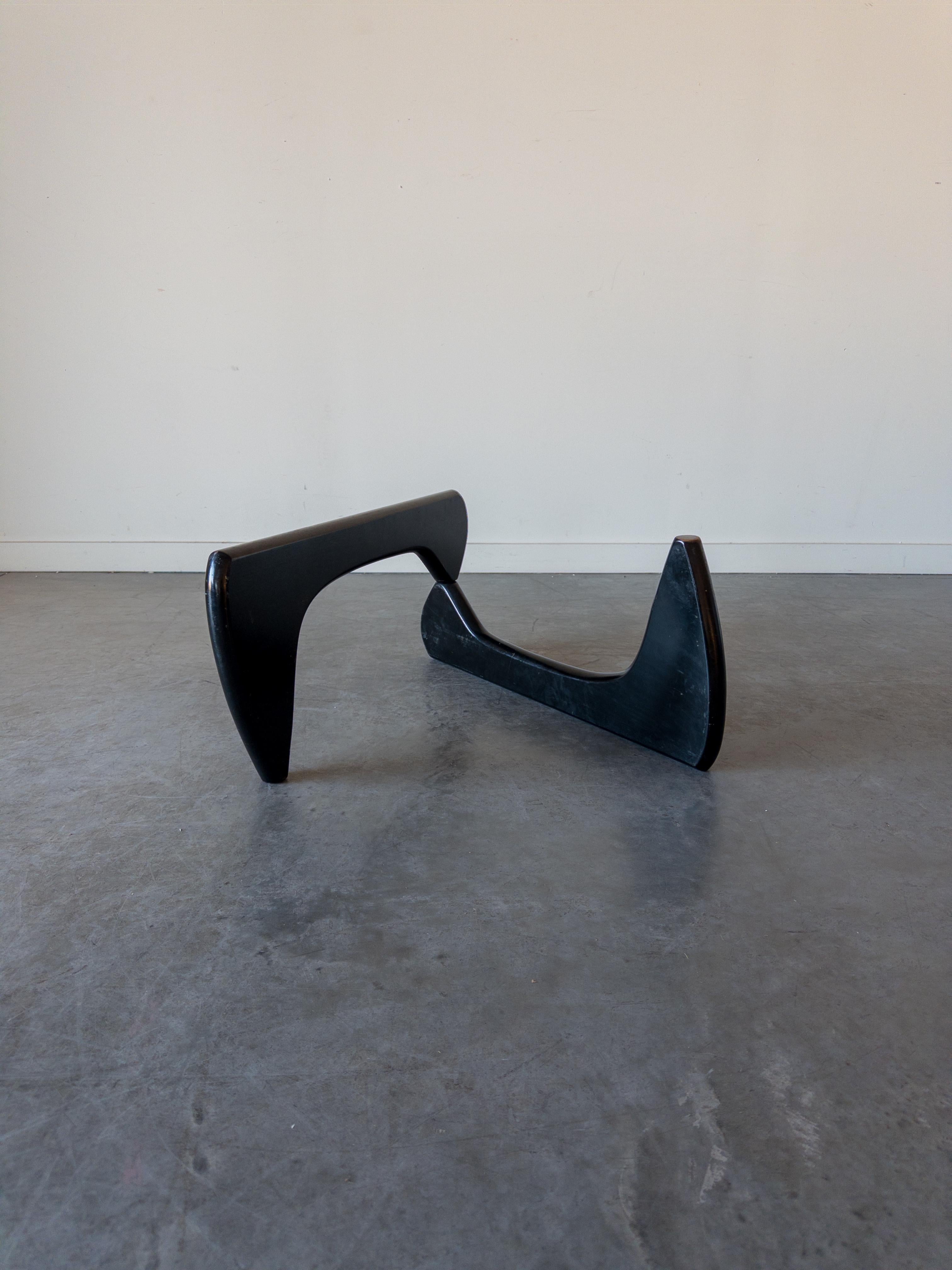 Noguchi Coffee Table, Model IN-50, initially designed by Isamu Noguchi in 1944. This example is from the 1950s and was produced by Herman Miller. The design features a thick piece of glass perched atop a sculptural interlocking solid birchwood