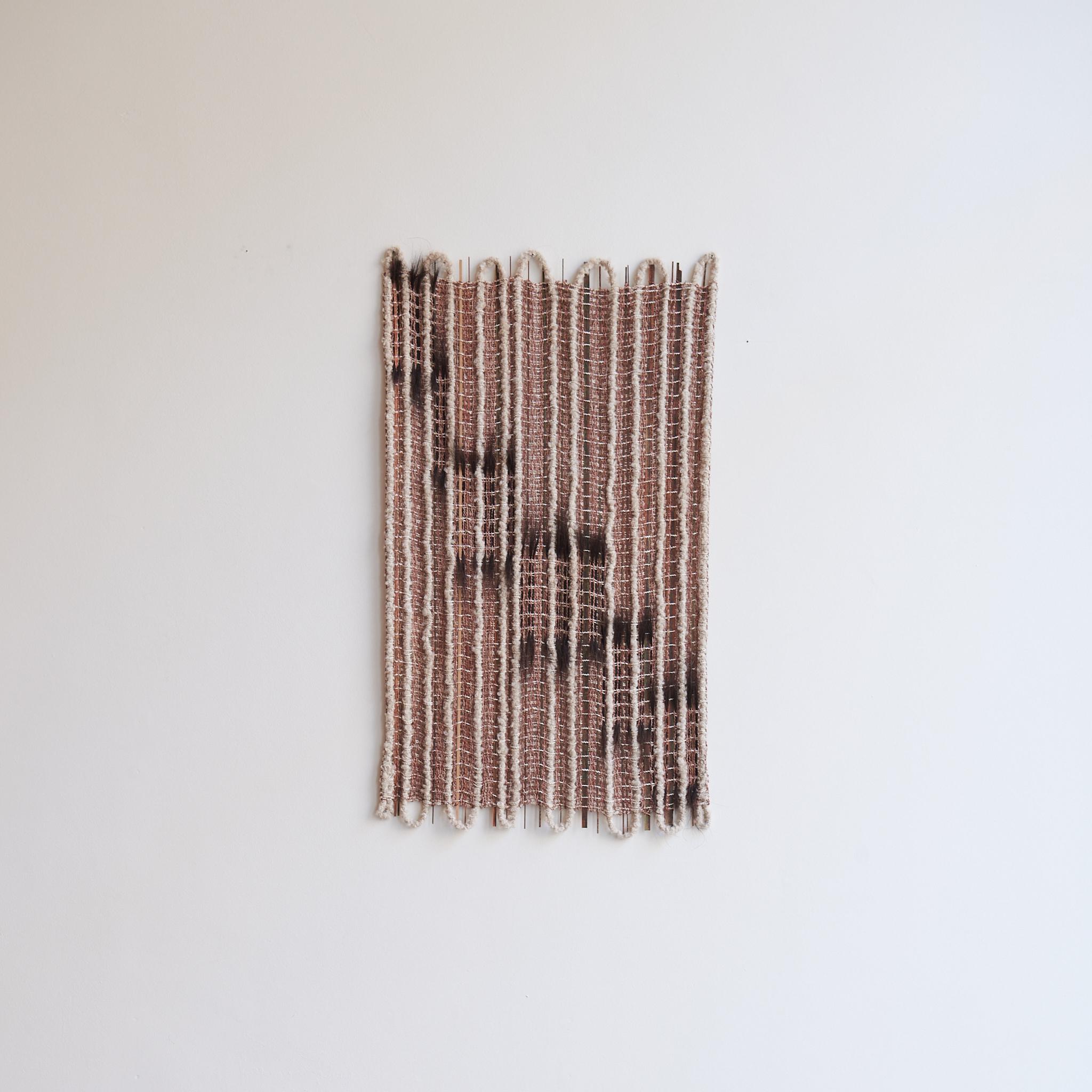 In Between #1 Wandskulptur von Delphine Cobbaert
Abmessungen: B 57 x  H 102 cm
MATERIALIEN: Wolle, Leinen, Jute, bemaltes Holz, Rosshaar. 

Delphine Cobbaert ist eine belgische Textilkünstlerin, Designerin und Kunsthandwerkerin. Ihr künstlerischer