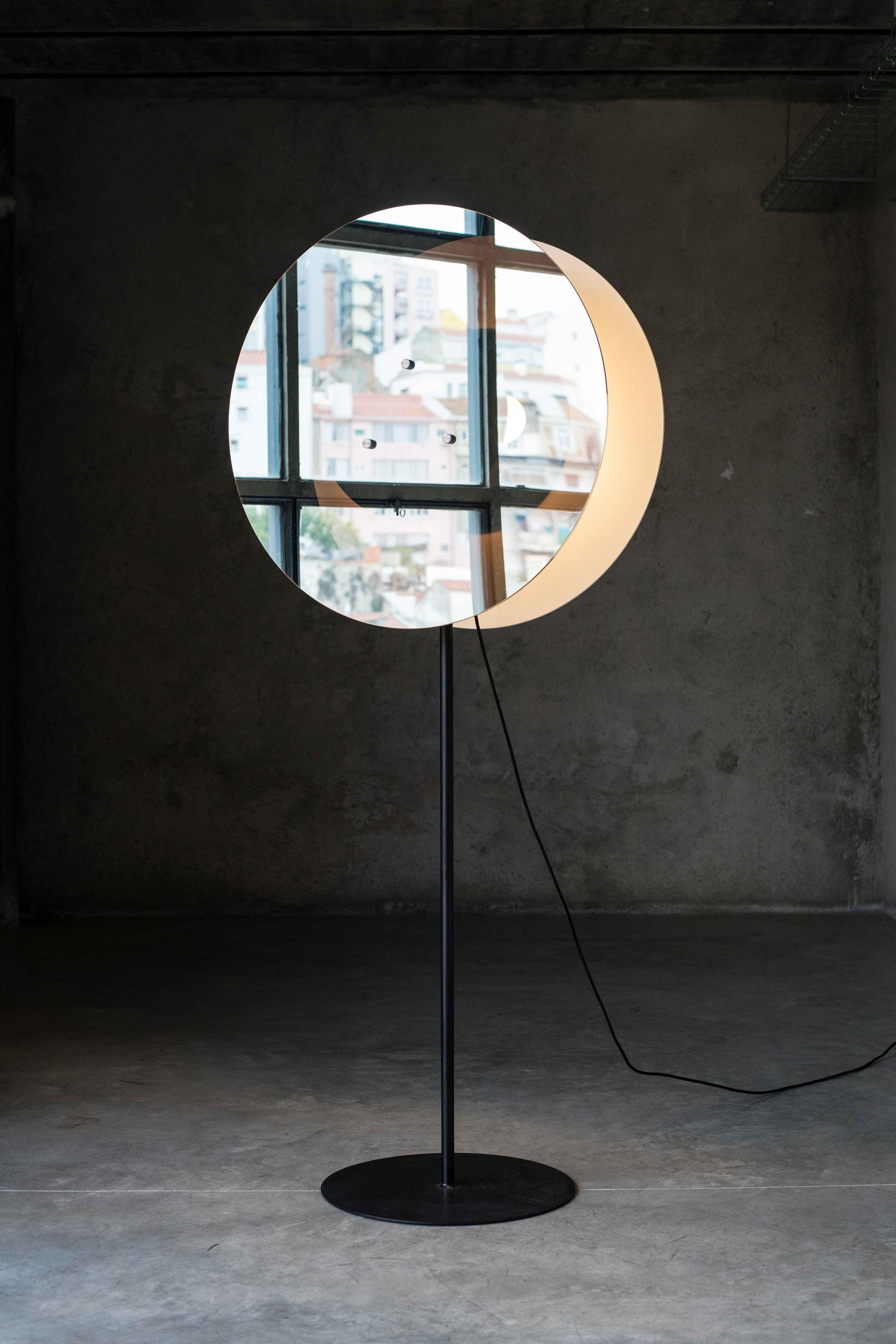 Entre deux lampes par MOB 
Édition limitée de 15 + 1 prototype
Designer : Javier Toro Blum (Chili)
Dimensions : H 175 x P 40 
MATERIAL : Structure en acier, verre miroir unidirectionnel, ampoules, câble noir.

Un faisceau de lumière est contenu dans