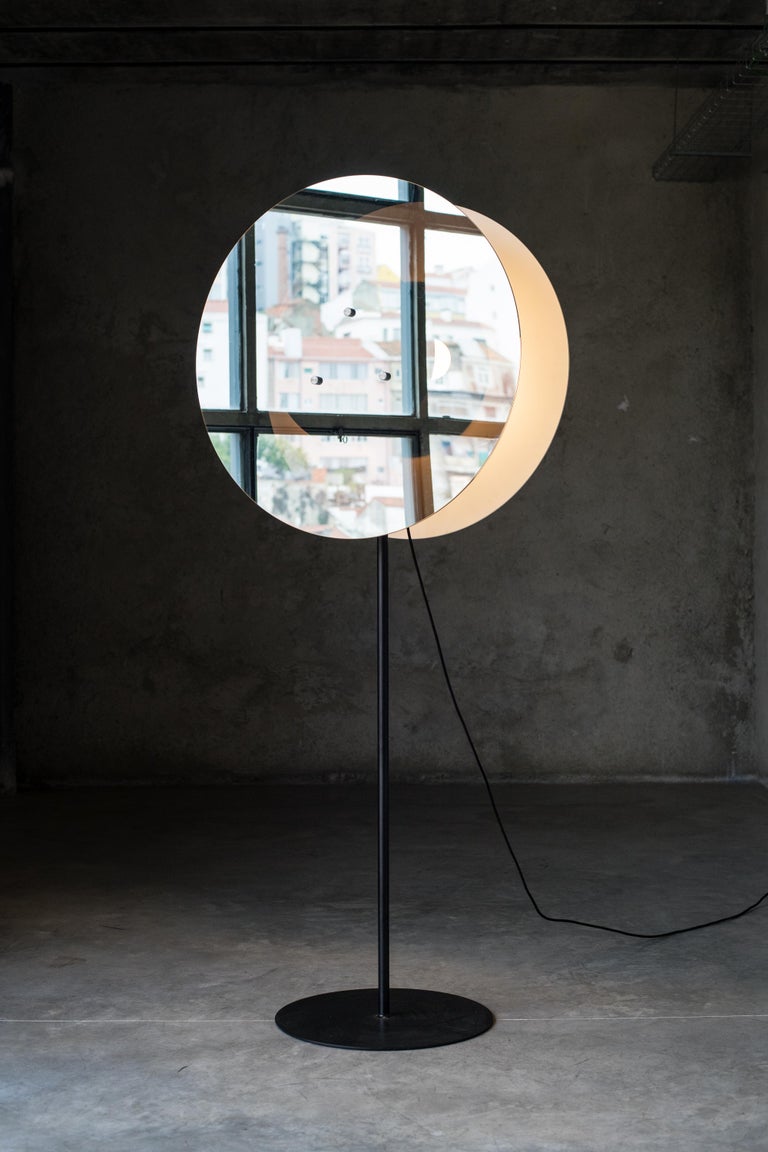 A beam of light is contained in two oval walls who rises like a silent lighthouse in the space. This lamp not only illuminates but also casts its shadow where light does not come out. The intermediate space allows light to flow like a halo, which