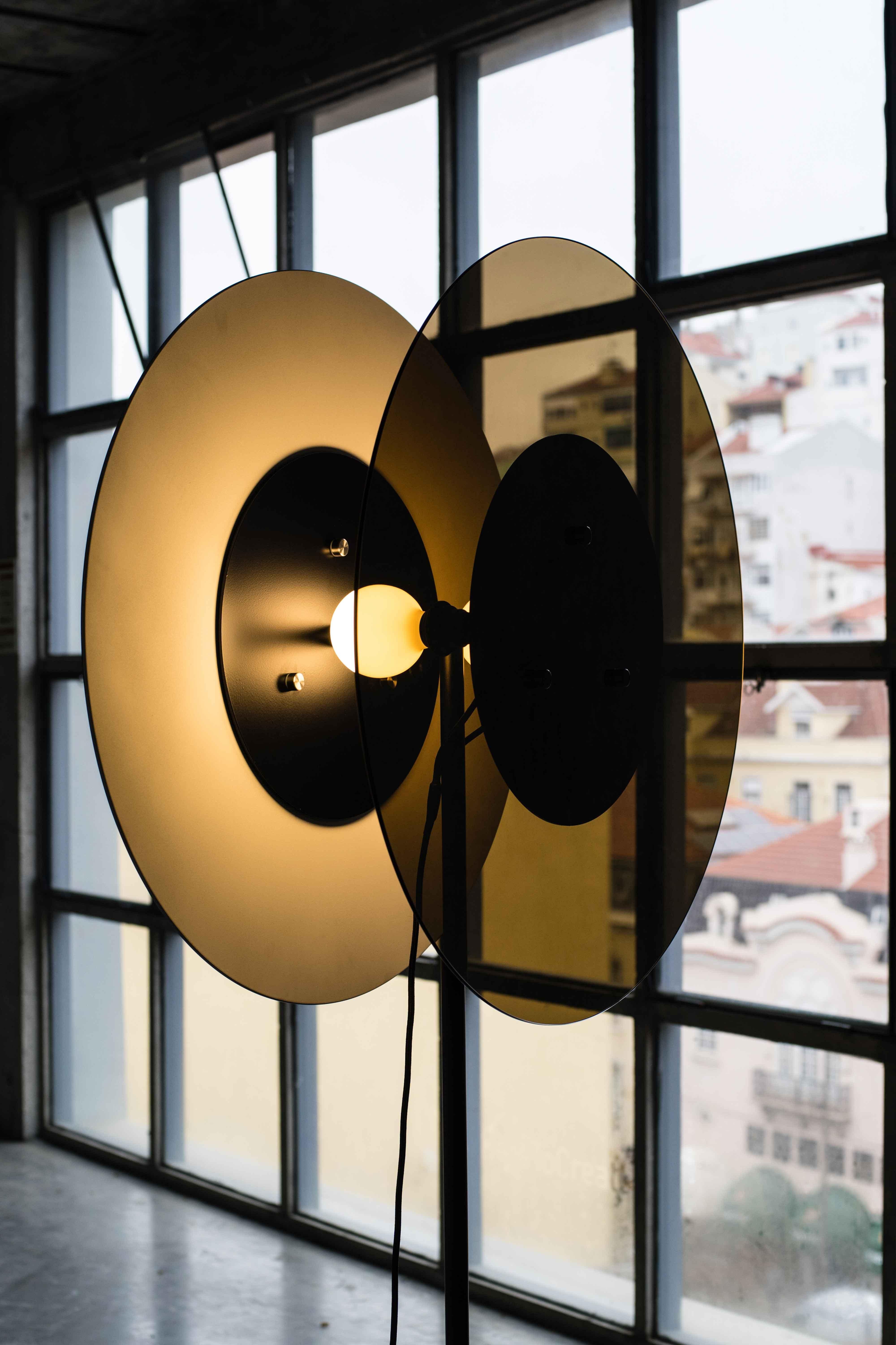 A beam of light is contained in two oval walls who rises like a silent lighthouse in the space. This lamp not only illuminates but also casts its shadow where light does not come out. The intermediate space allows light to flow like a halo, which