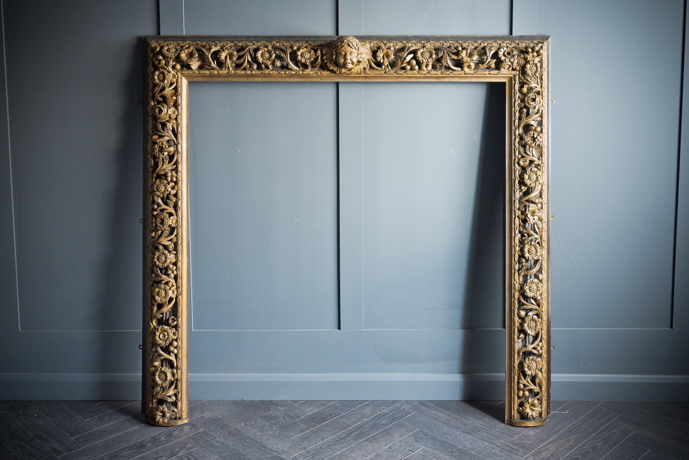 In the manner of Grinling Gibbons, a rare and beautifully hand carved worn gilt over Douglas Fir English overmantle and historically replaced foxed mirror with jade marble base plate, late 18th century in Douglas fir.
