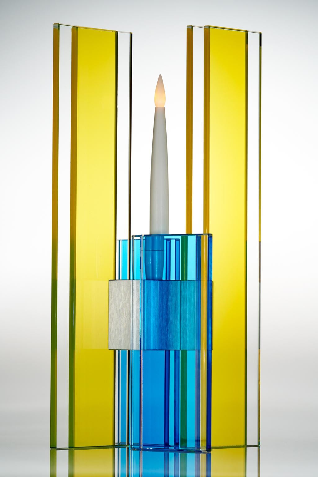 This polished glass candleholder from the Deco series is designed by world renowned glass artist, Sidney Hutter. With 40 years of experience in the contemporary glass and fine art world, Sidney now creates illuminated designs for the home. Create a