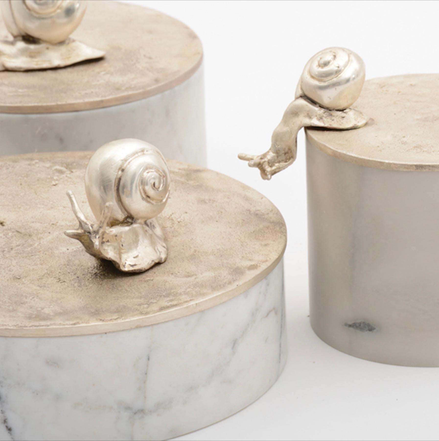 Disponible dès maintenant au Showroom Elan Atelier NY et prêt à être expédié !

La boîte à souvenirs sculpturale de Caracole avec une base sculptée à la main en marbre blanc et un couvercle en bronze argenté mat avec deux escargots. Un élégant