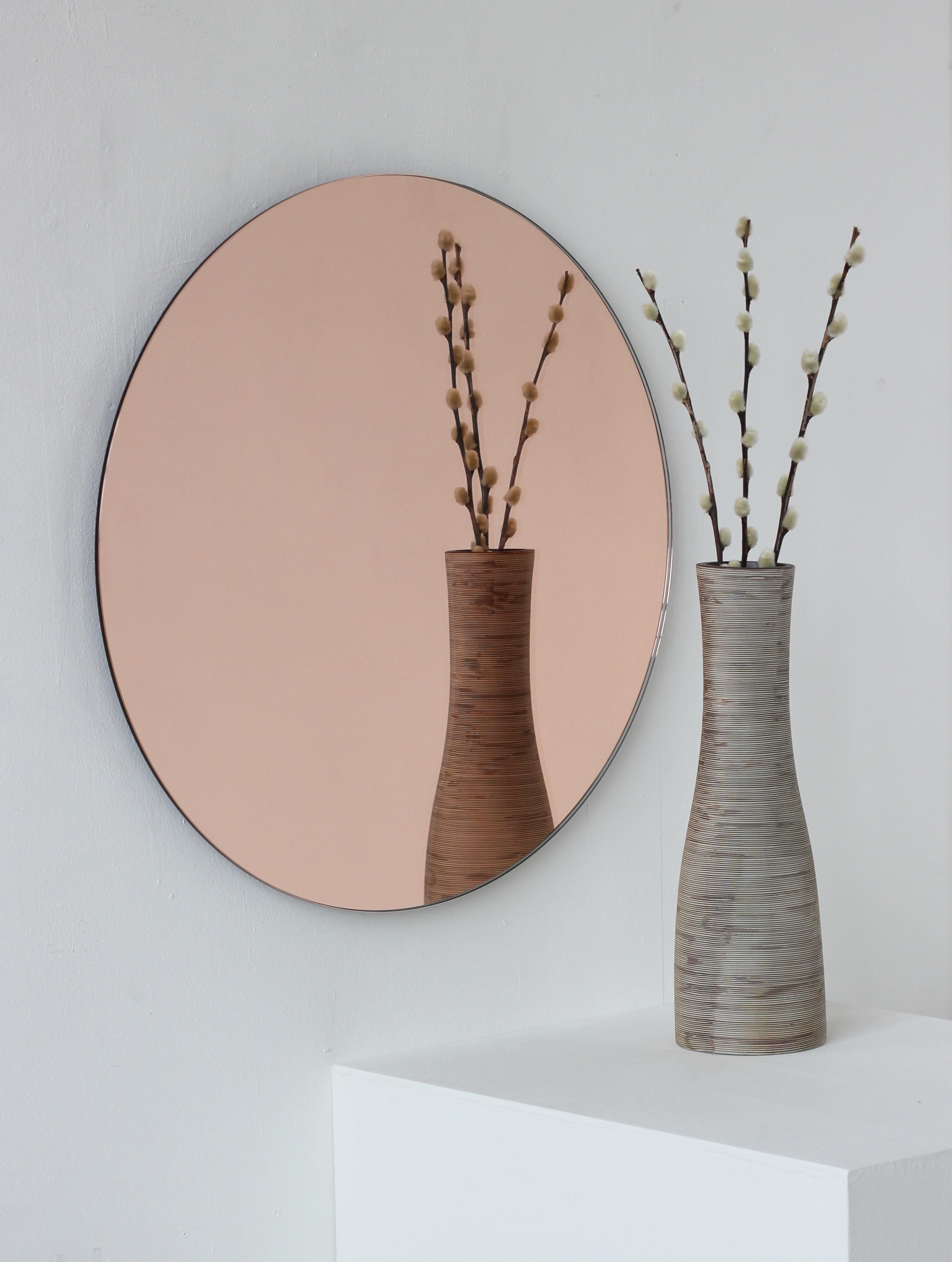 Available from stock.

Charming and minimalist rose gold / peach tinted round frameless mirror with a floating effect. Quality design that ensures the mirror sits perfectly parallel to the wall. Designed and made in London, UK.

Fitted with