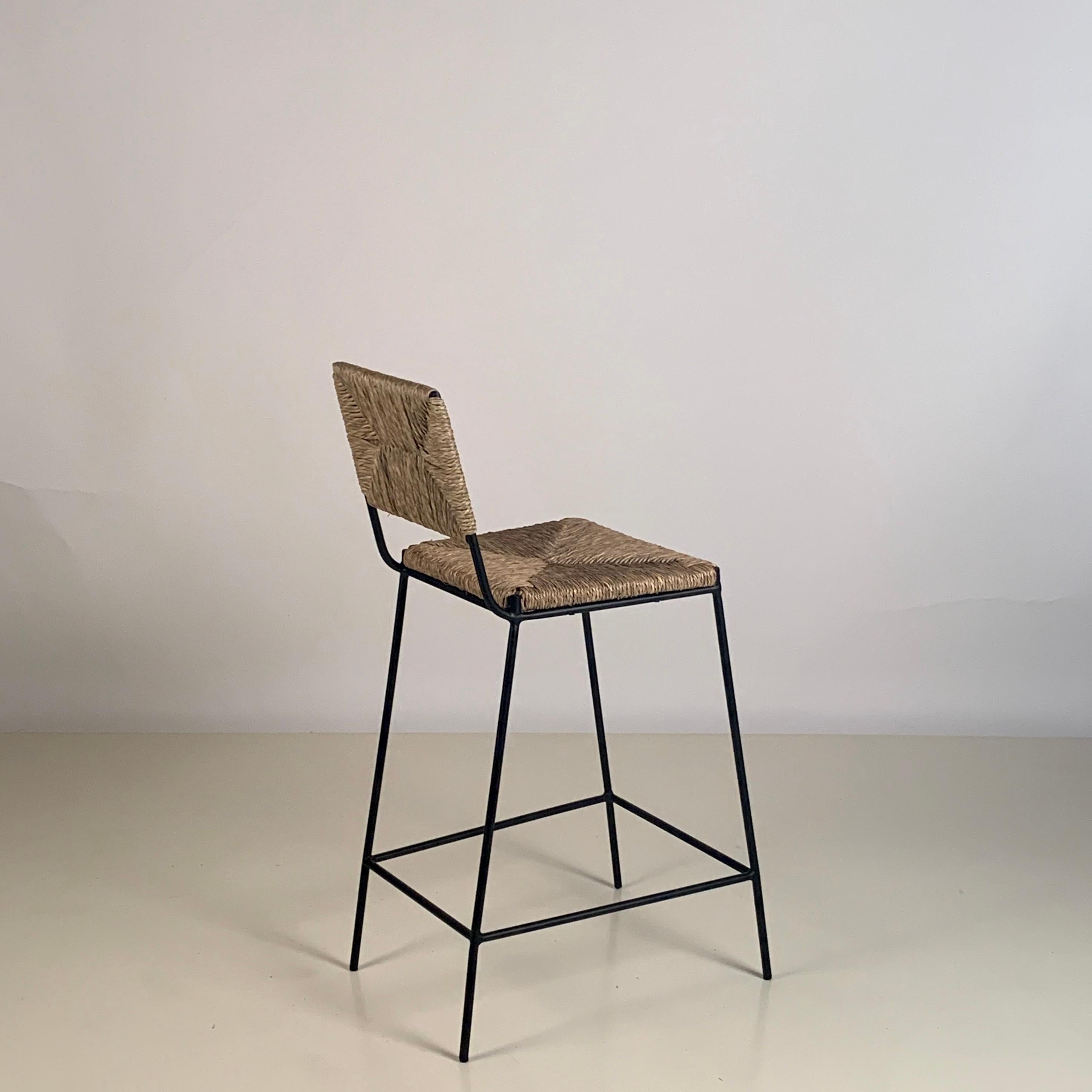 Pair of 'Campagne' counter height stools by Design Frères.

Chic combination of slender but sturdy powder coated steel frames with handwoven rush seats and backs. Extra support under the rush seat for durability. Durable plastic caps on the feet to