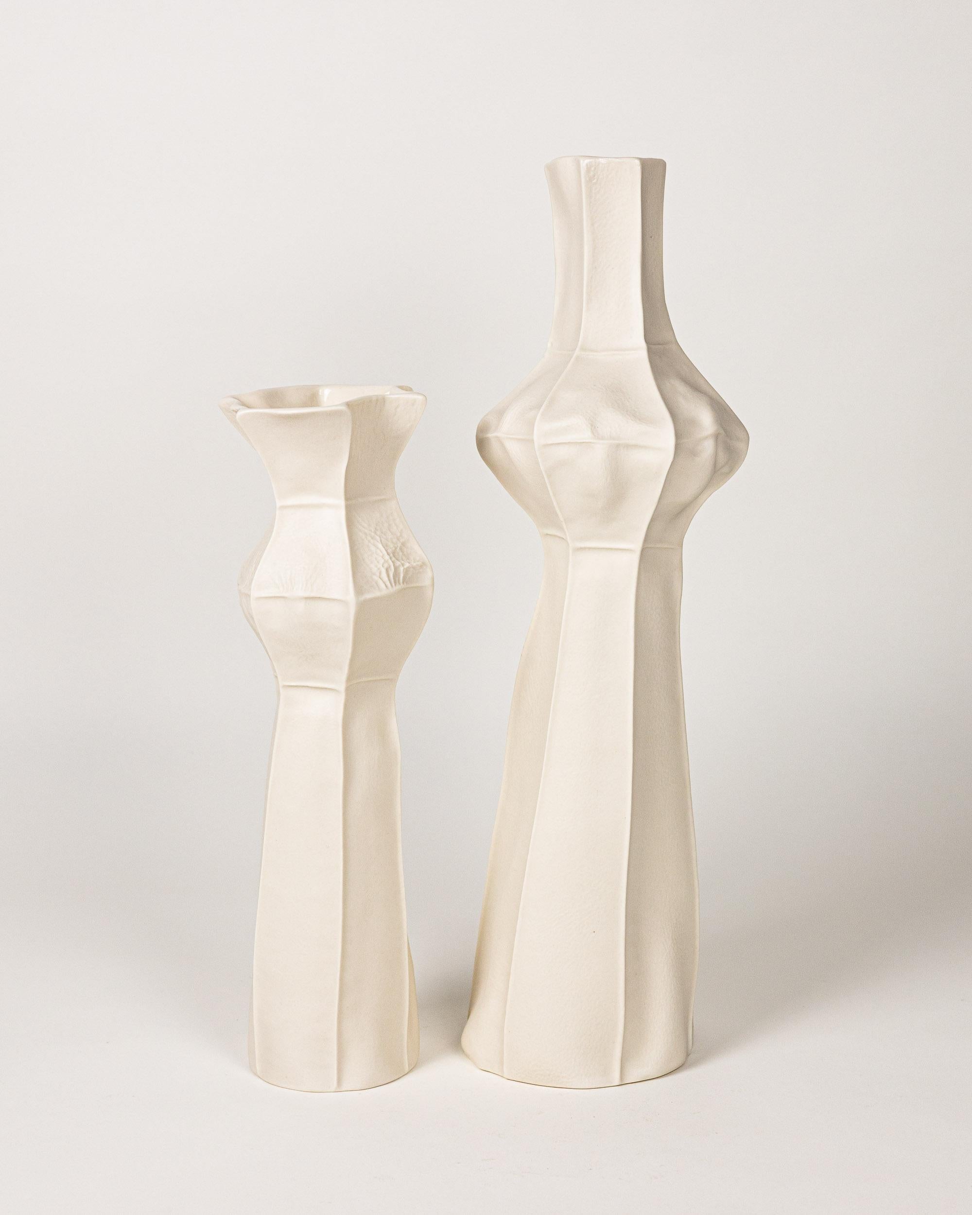 A pair of tall and tactile porcelain vases with a leather textured exterior surface and clear glazed interior. This specific set was inspired by skyscrapers in the city. 

As a result of the production process each item is one-of-a-kind. Set