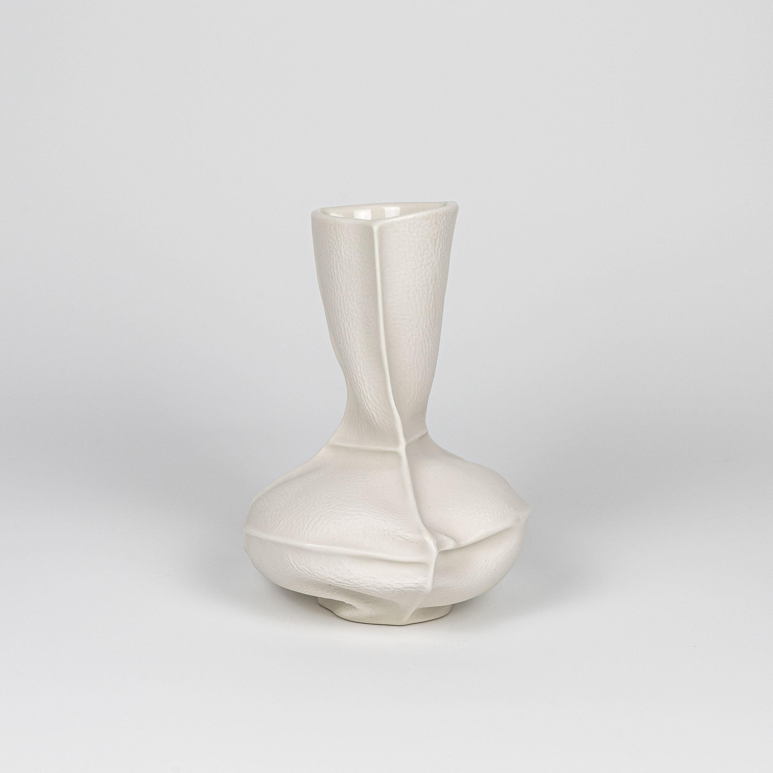 Un vase à fleurs en porcelaine à la forme et à la texture organiques, réalisé en coulant de la porcelaine liquide dans des moules en cuir cousus. Une glaçure transparente est appliquée sur la surface intérieure. En raison du processus de production,