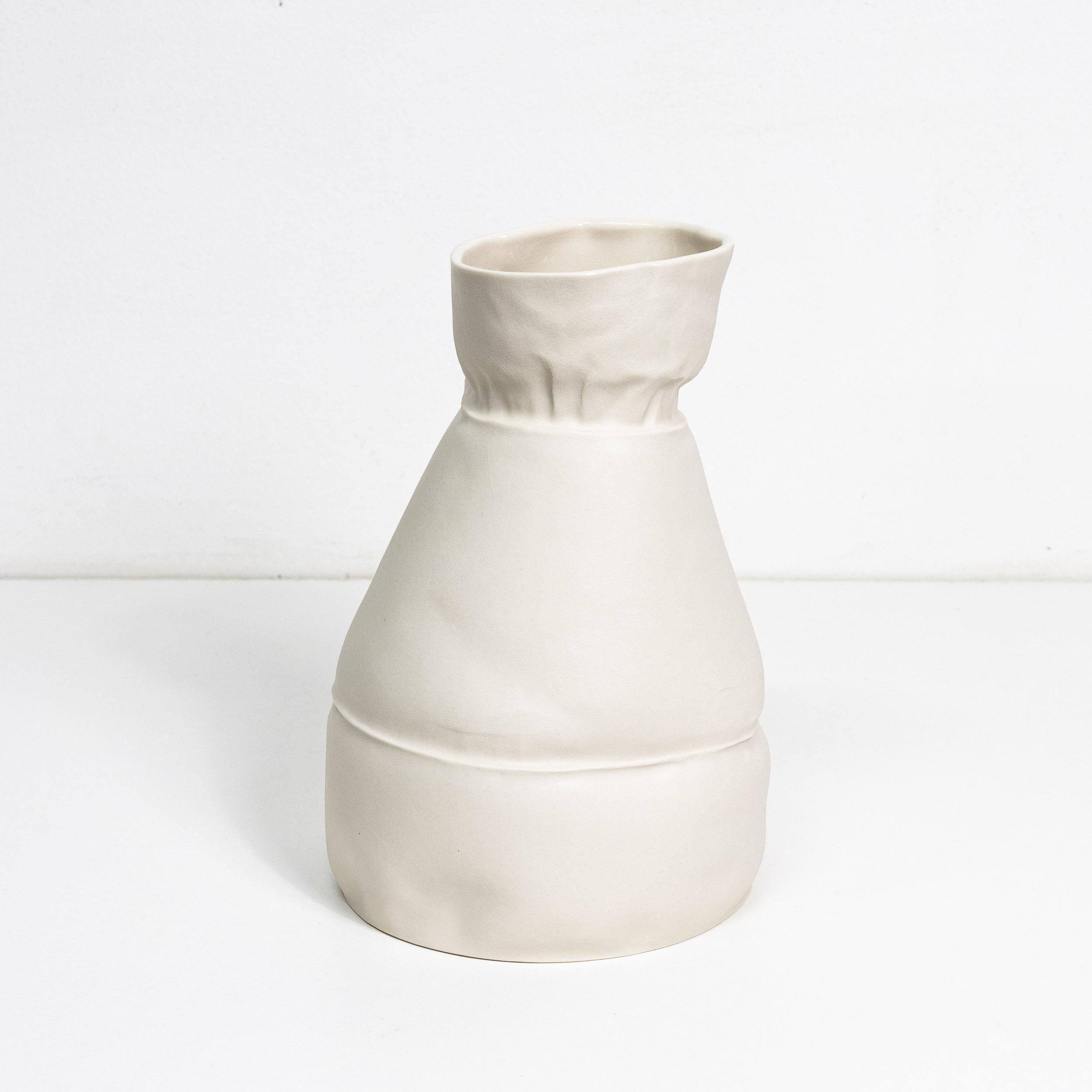 A porcelain flower vase with an organic form and texture, made by casting liquid porcelain in sewn leather molds. Clear glaze applied on interior surface. As a result of the production process each vase is one-of-a-kind. 

The vessel is watertight