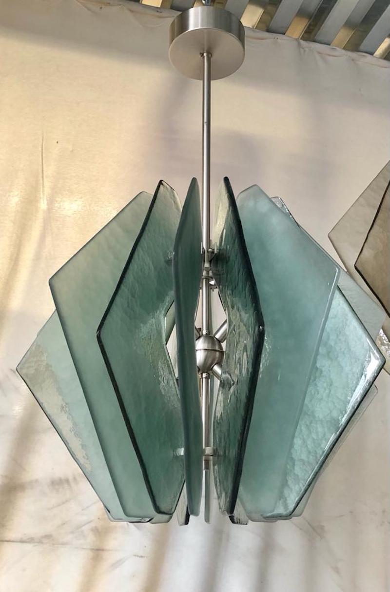 Splendid Murano glass chandelier with a particular gradation of aqua green color. Its design is also very particular round but composed of triangular handkerchiefs. The Murano furnaces create an indisputable timeless design, simple but elegant at
