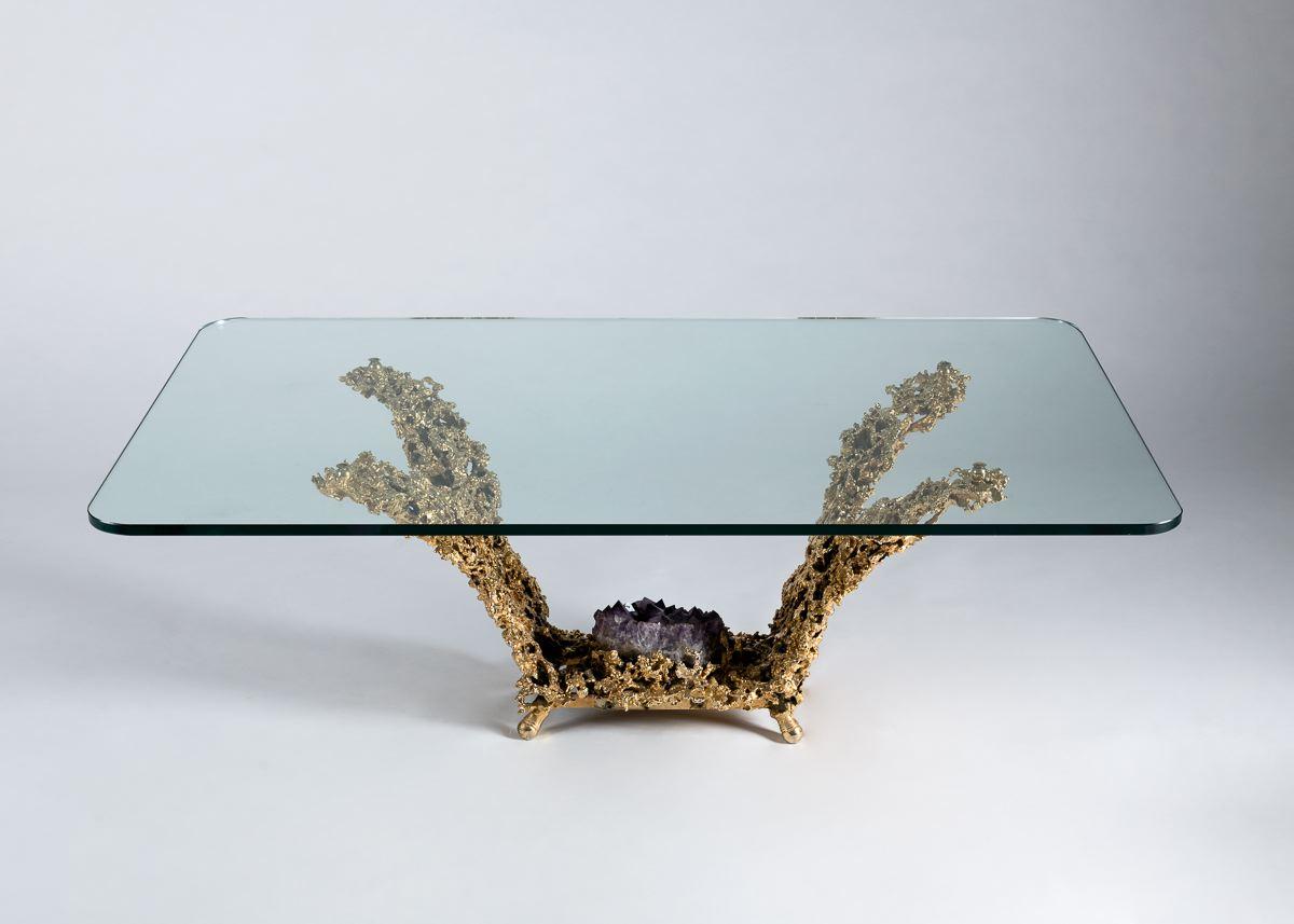 This table’s arresting, gilt bronze base mimics lightning in hue, form, and arrangement. At the base’s center lies a large amethyst, and the piece is crowned with a wide, rectangular glass top.
   