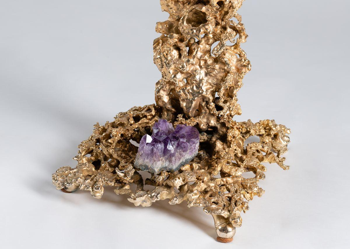 This side table, modeled after one of Boeltz's mature Eclaté pieces, possesses and arresting gilt bronze base mimicking lightning in hue, form, and arrangement. At the base’s centre lies a large amethyst, and the piece is crowned with a wide,