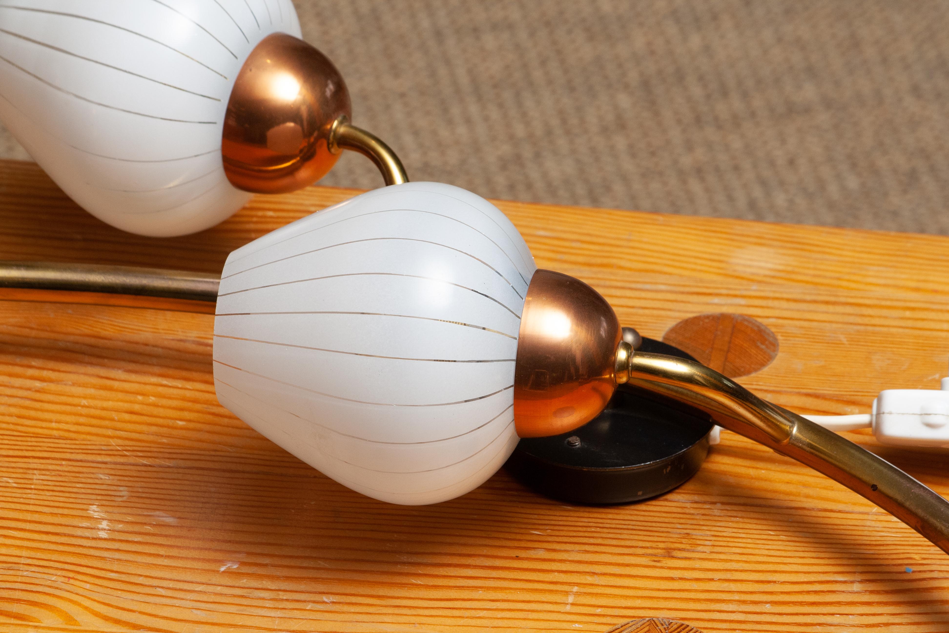 Beautiful brass wall light in the chape of a brach from Sweden.
This lamp consists of a copper base with five white glass shades like a branch with berries.
The shades have transparent lines making it a nice shining light.
The lamp is in a very nice