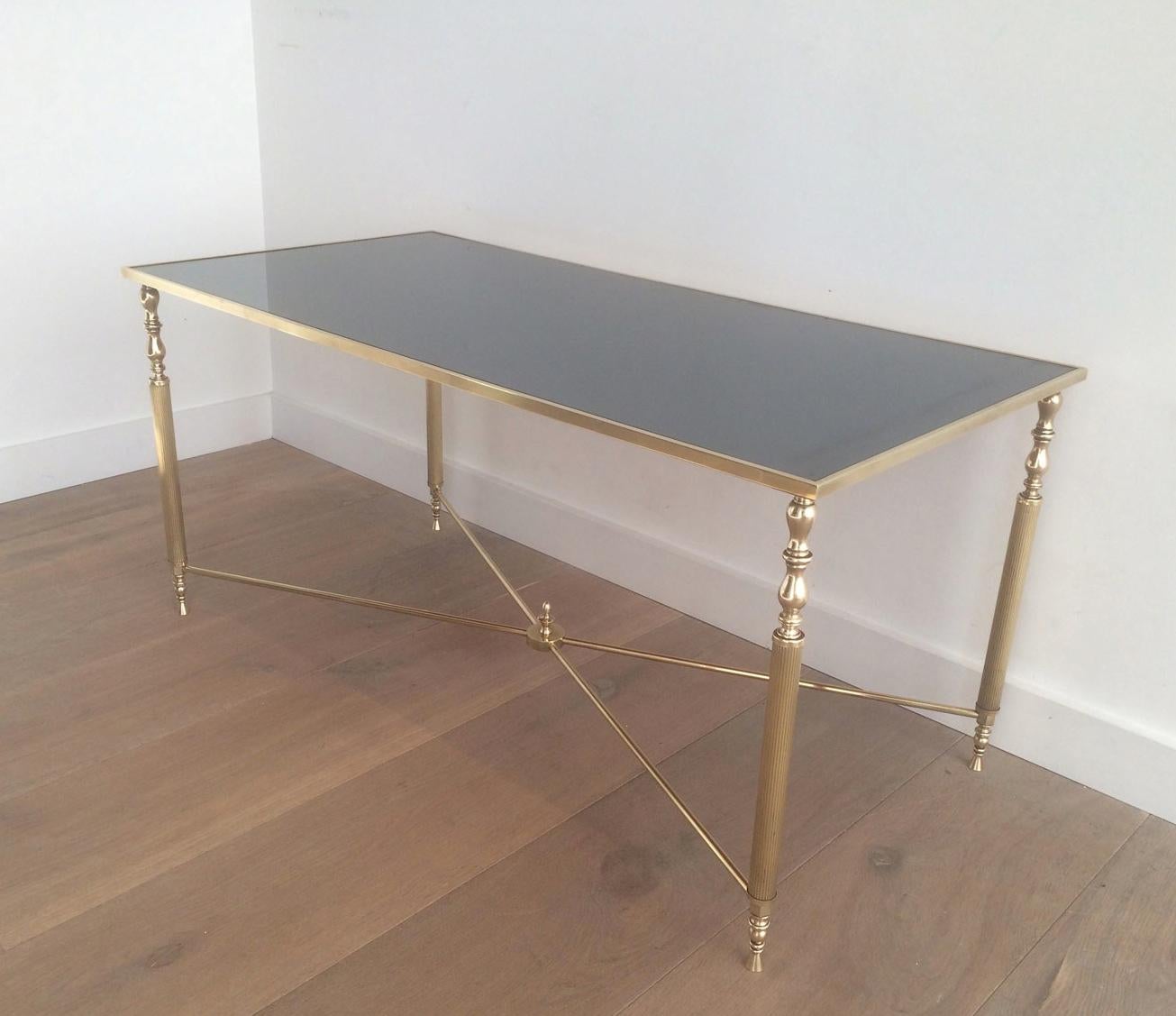 In the style of Maison Jansen. This very nice and elegant neoclassical style coffee table is made of brass with a beautiful original blueish mirror top surrounded by a brass frame. This is a French work, circa 1940.