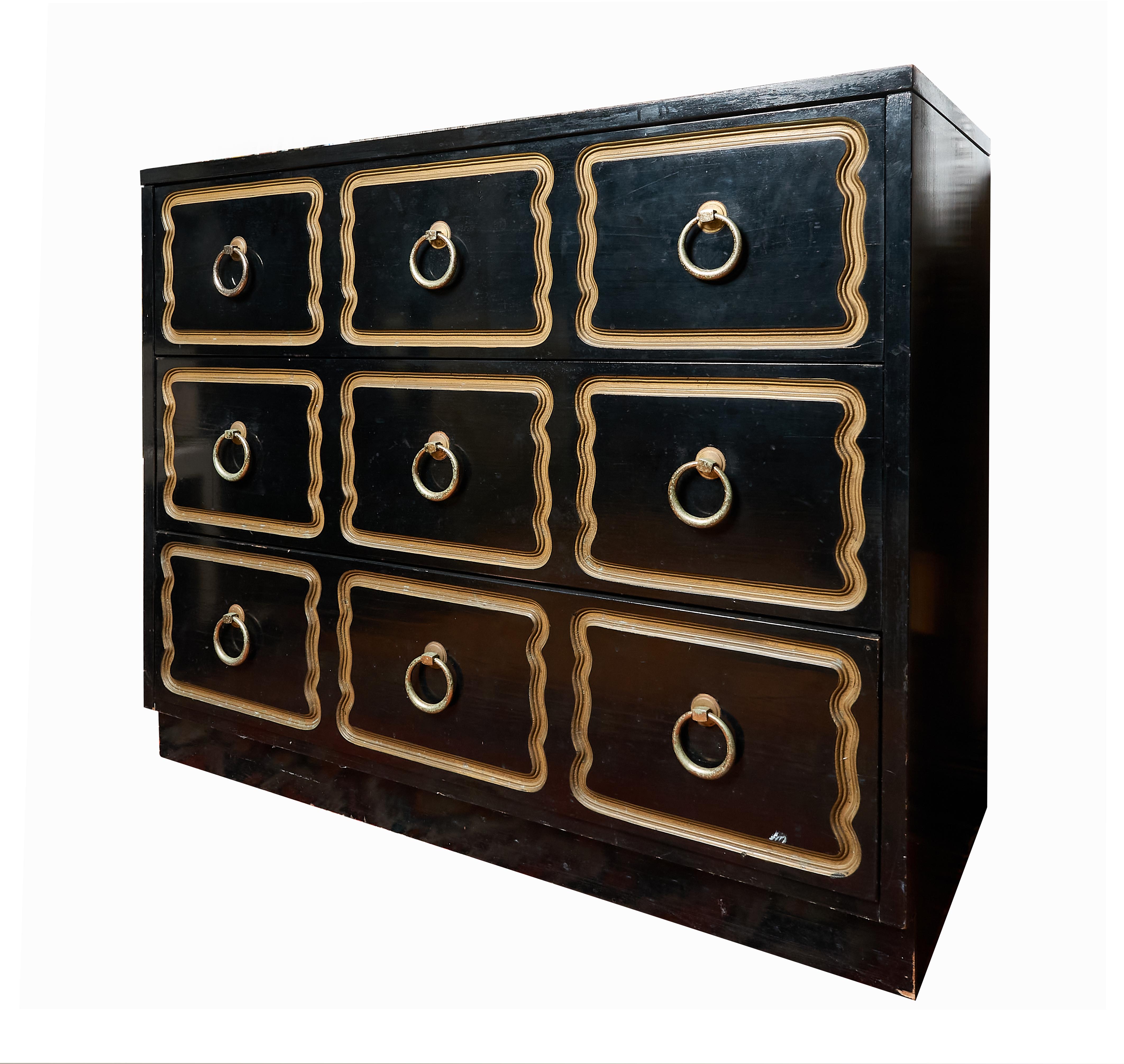 Nicely done reproduction of the iconic Dorothy Draper Espana dresser. Done in black satin painted finish with flat gold trim and brass tone large ring hardware. Some slight wear to the edges and hardware. Back is also painted black. There is no