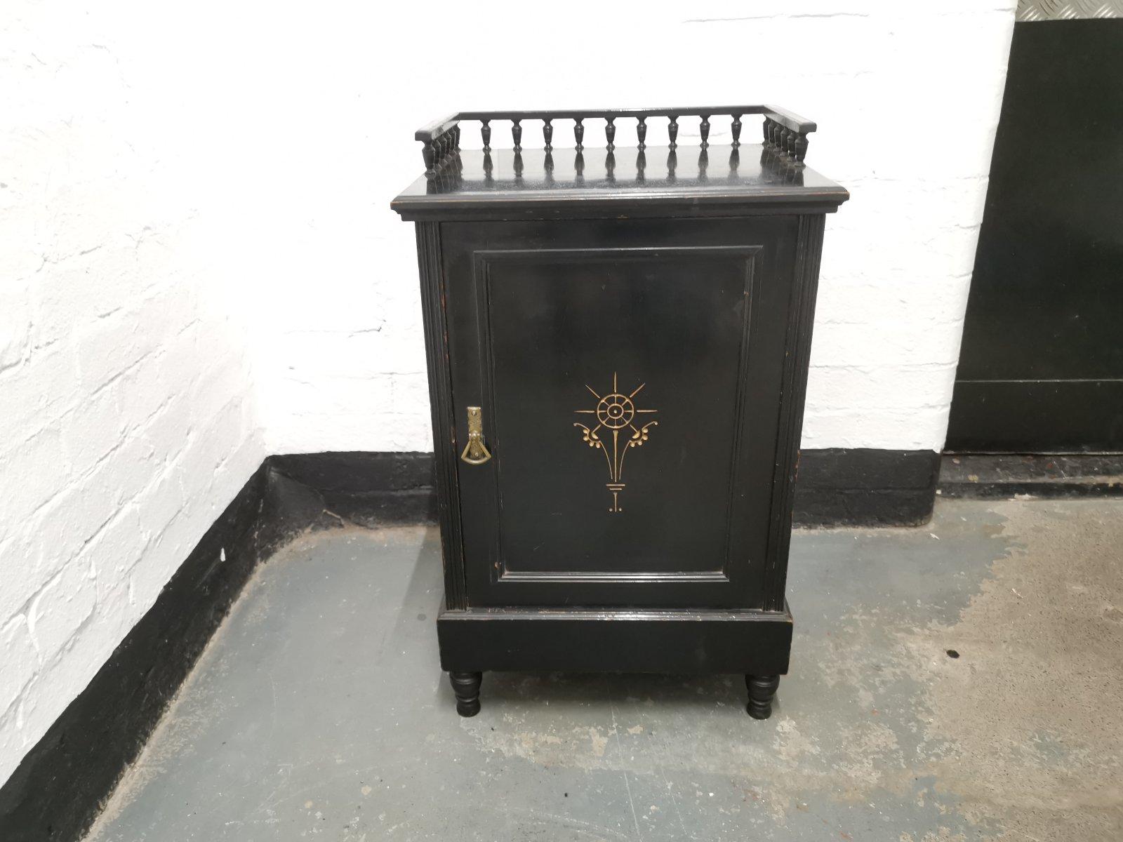 In the style of Dr. C dresser, probably made by Gillows.
A fine English Aesthetic Movement ebonized walnut bedside cabinet with a three-quarter gallery to the top, a single panelled door below with an incised and gilded stylized floral detail to