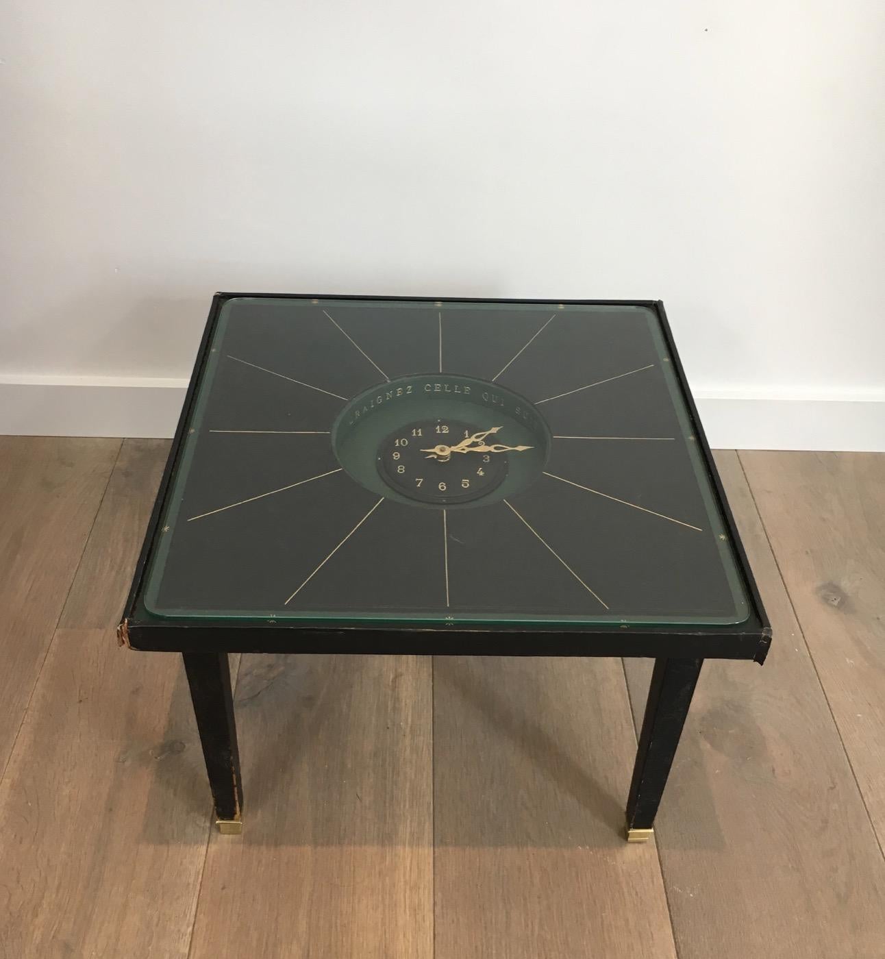 This rare small coffee table is made of leather and brass with a clock in its center and a gold inscription in French: 