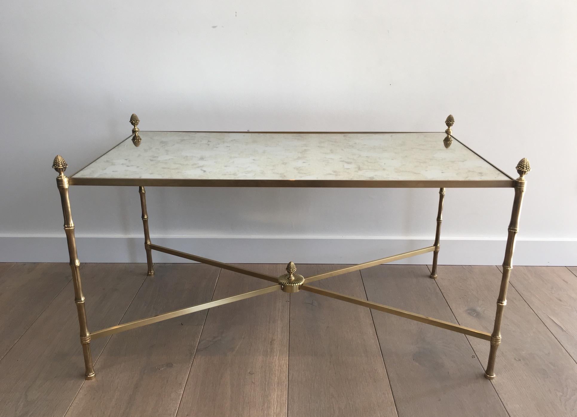 This neoclassical coffee table is made of bronze and brass with fine faux-bamboo feet and nice finials on each corner that we can find on the center of the stretcher as well. The shelf is made of a faux-antiques mirror in the style of the old