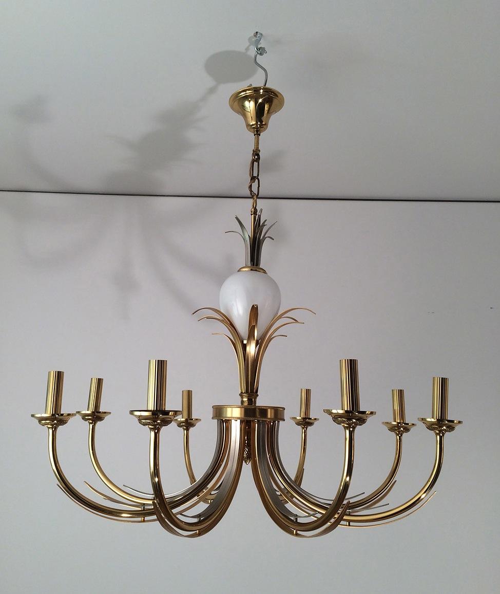This decorative chandelier is made of a gilt and brushed metal with a porcelain egg. This fixture has got 8 arms. This is a French work in the style of famous Maison Charles, circa 1970.
