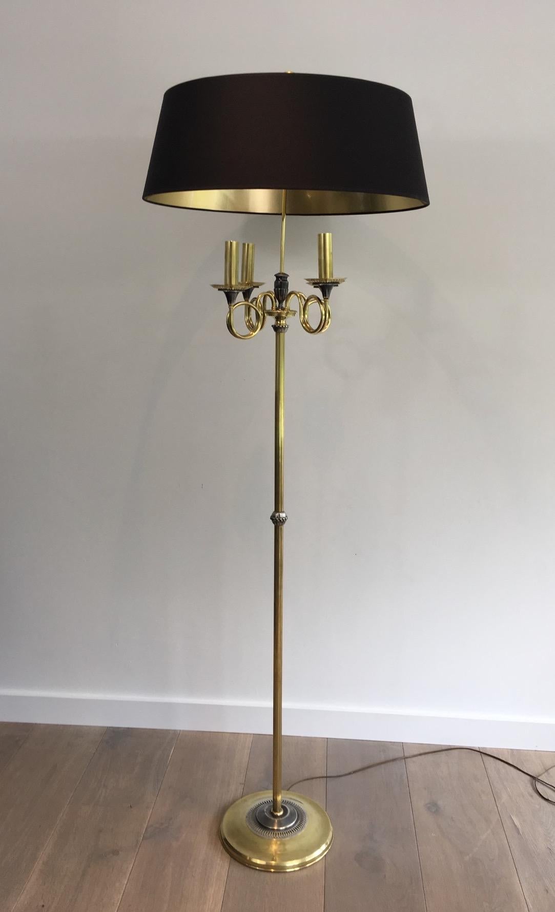 This very nice neoclassical style floor lamp is made of  silver plated and brass. The lamp is composed of 4 lights on top of 4 brass sleeves on trumpets. It has a brass ring on top of the lamp. This is a French work in the style of Maison Charles.
