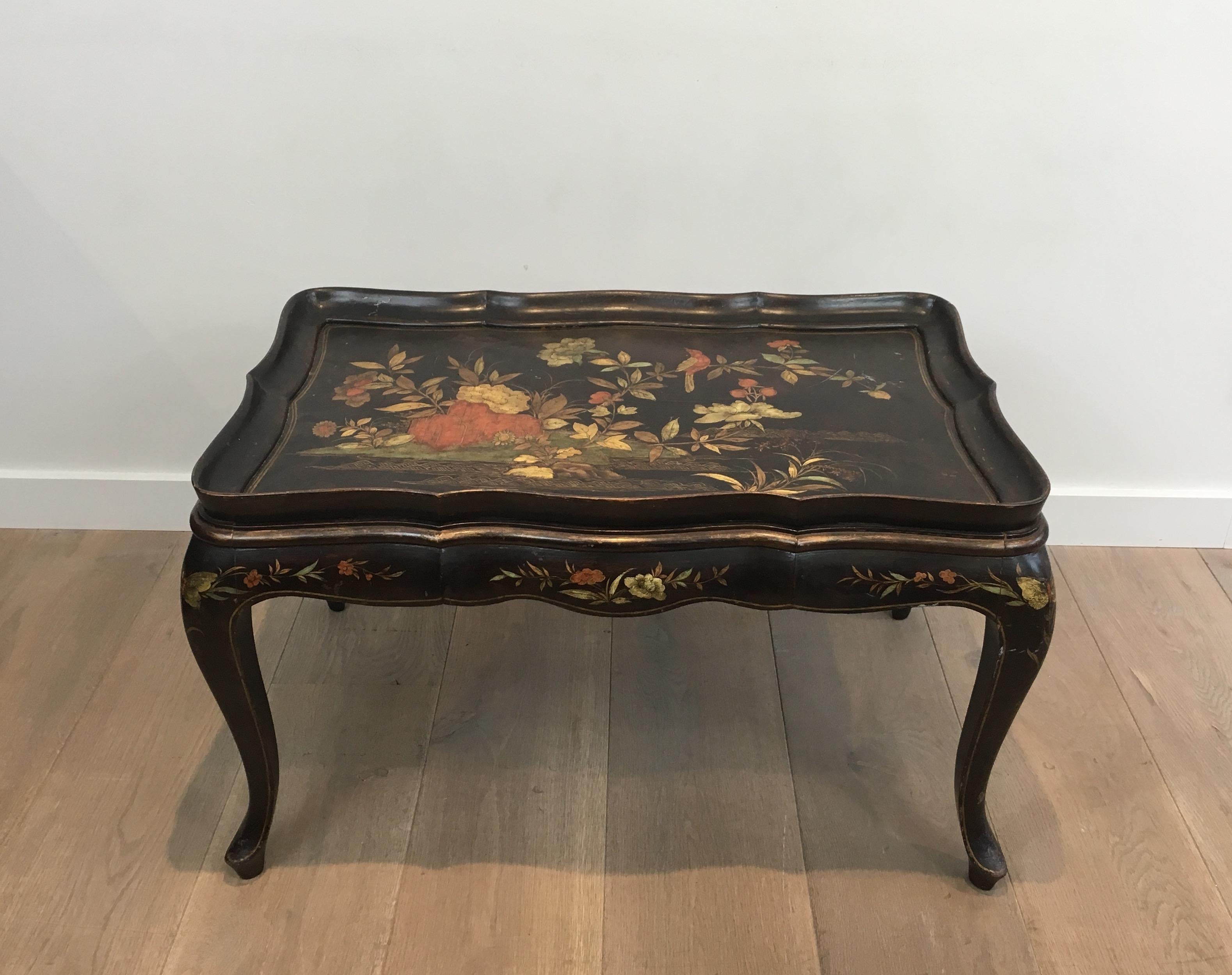 This neoclassical style coffee table is black lacquered with a beautiful polychrome and gilt flowers decors. This is a very elegant coffee table in the style of famous French designer Maison Hirch, circa 1940.