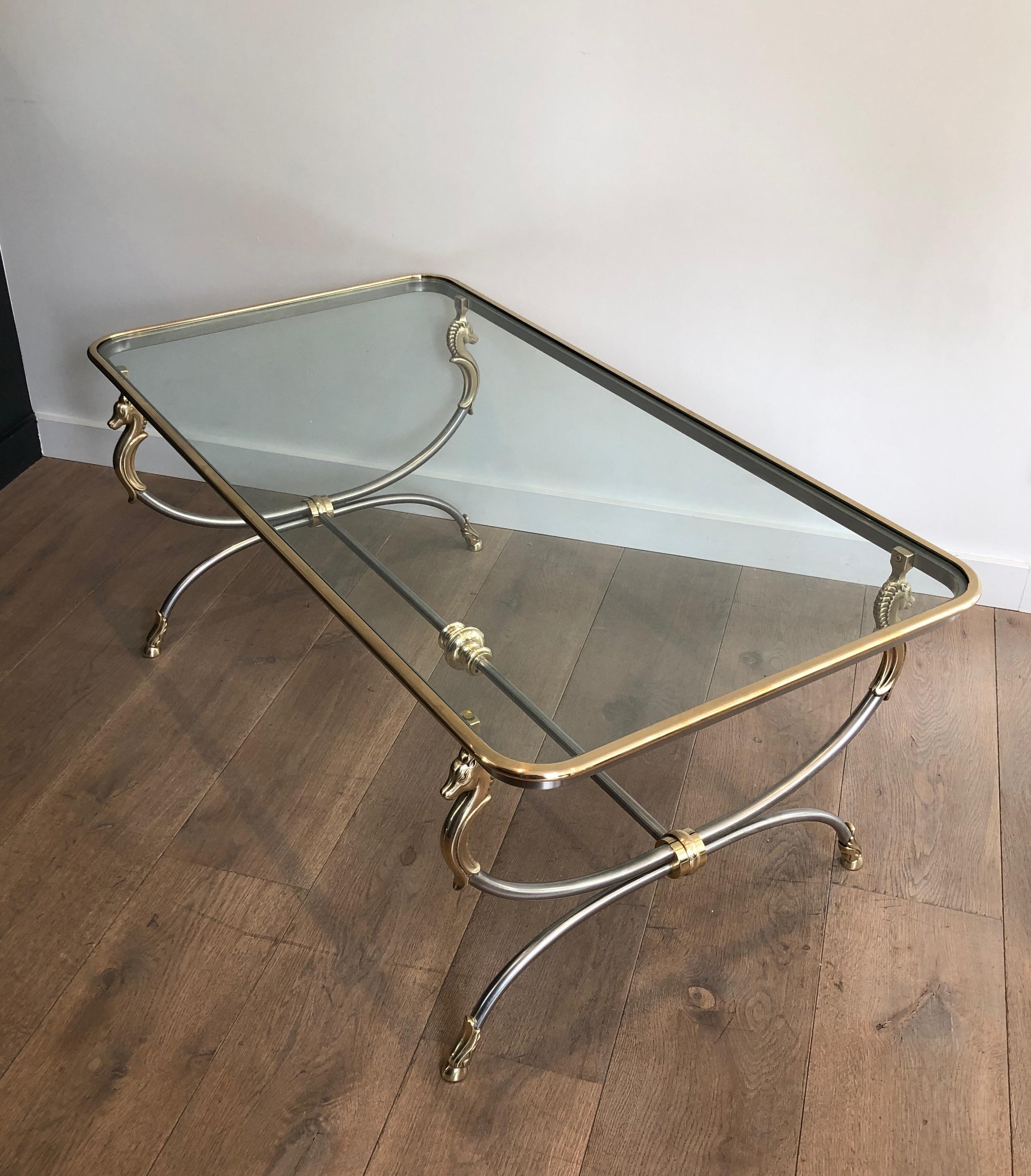 This beautiful neoclassical style coffee table is made of brushed steel and brass. This is a large cocktail table, rounded on the corners with elegant Horse heads and shoes. This is nice French work, in the style of Maison Jansen, circa 1970.