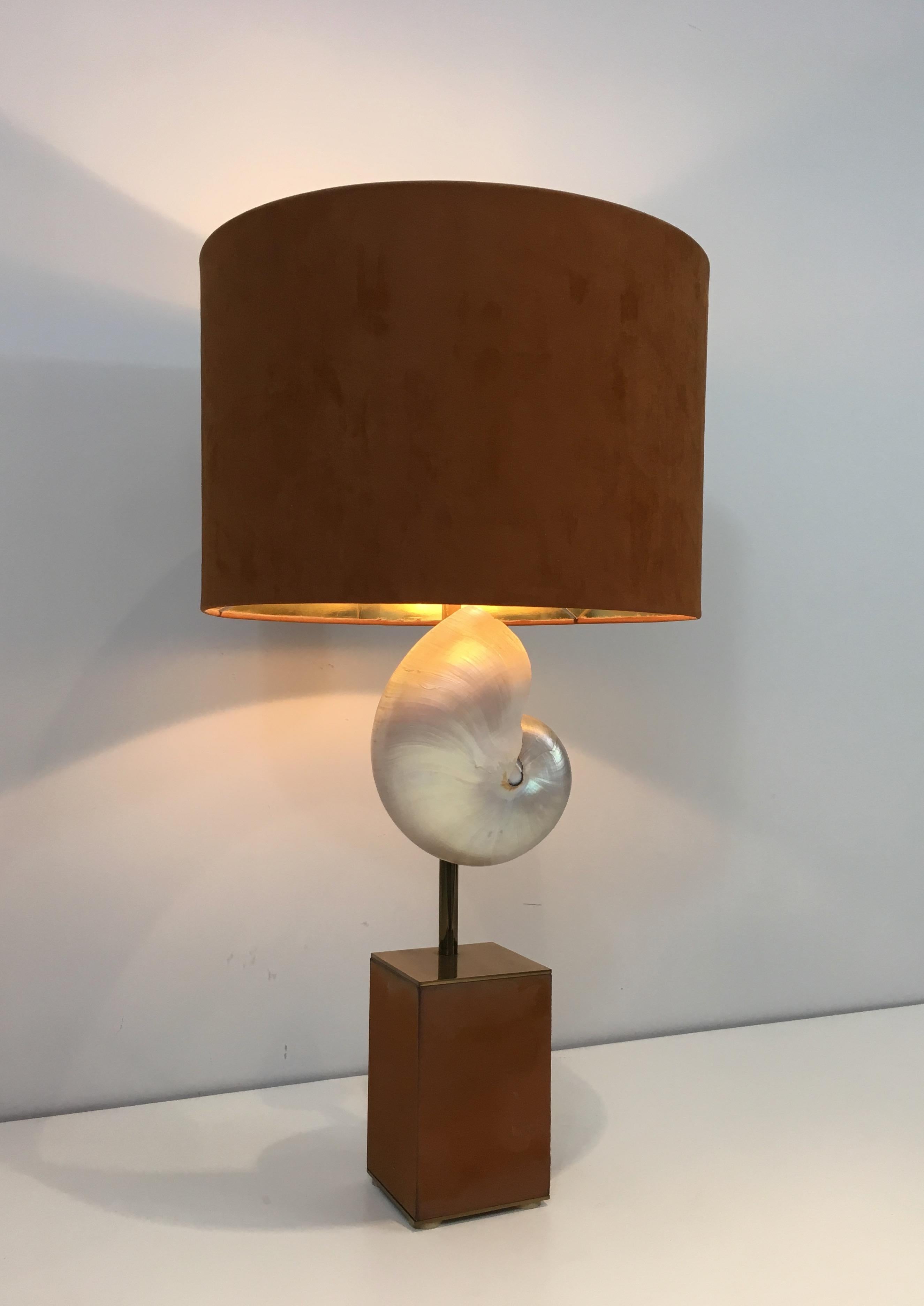 This beautiful nautilus shell is mounted into a table lamp. This lamp is made of brass and suedine, on a wooden base. Suedine is a bit used. This is a french work, in the style of famous Maison Jansen, circa 1940.