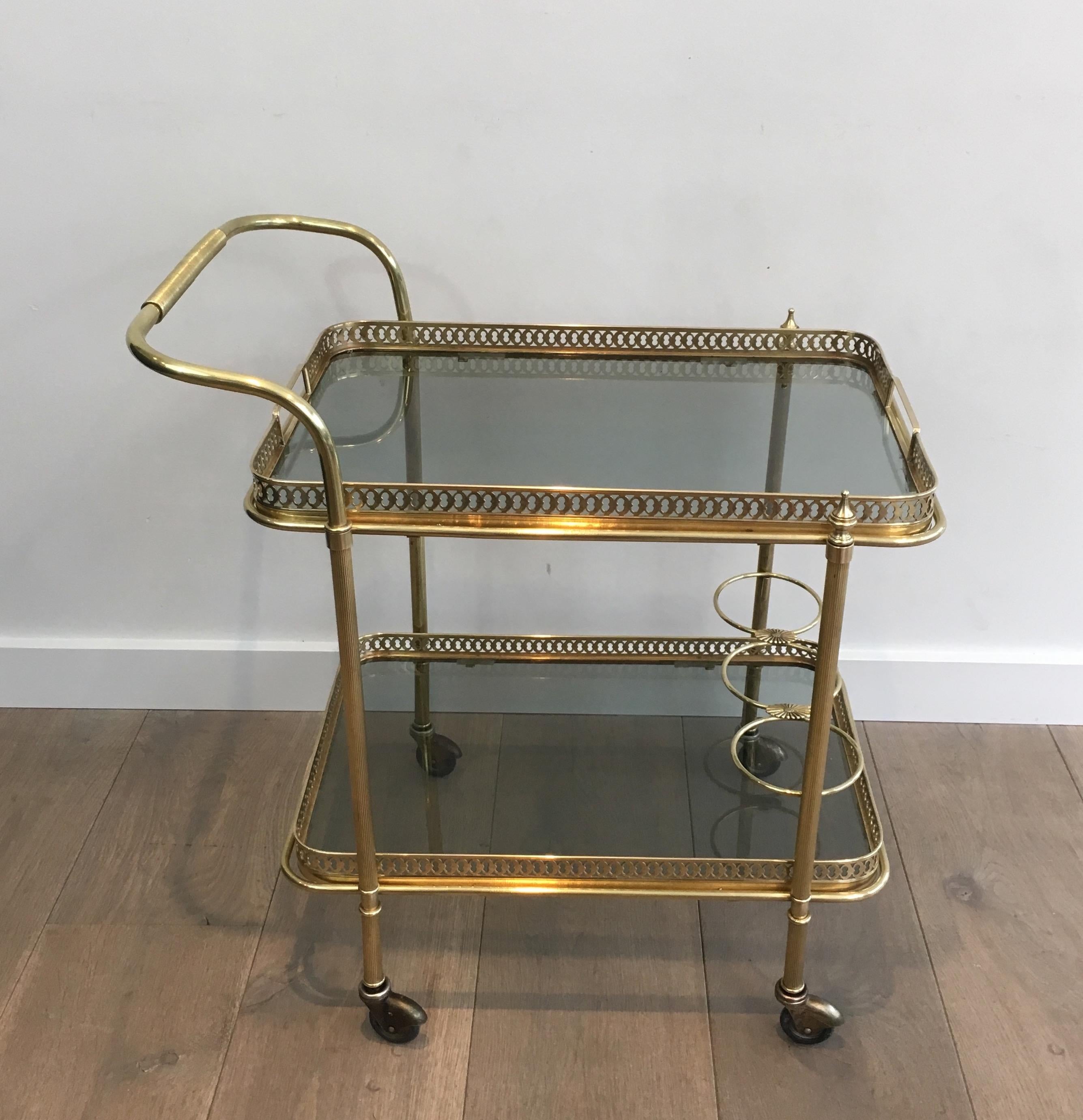 This neoclassical drinks trolley is made of brass with blueish glass shelves. This is a very Fine work of very good quality. This bar cart is in the style of famous French designer Maison Jansen, circa 1940.