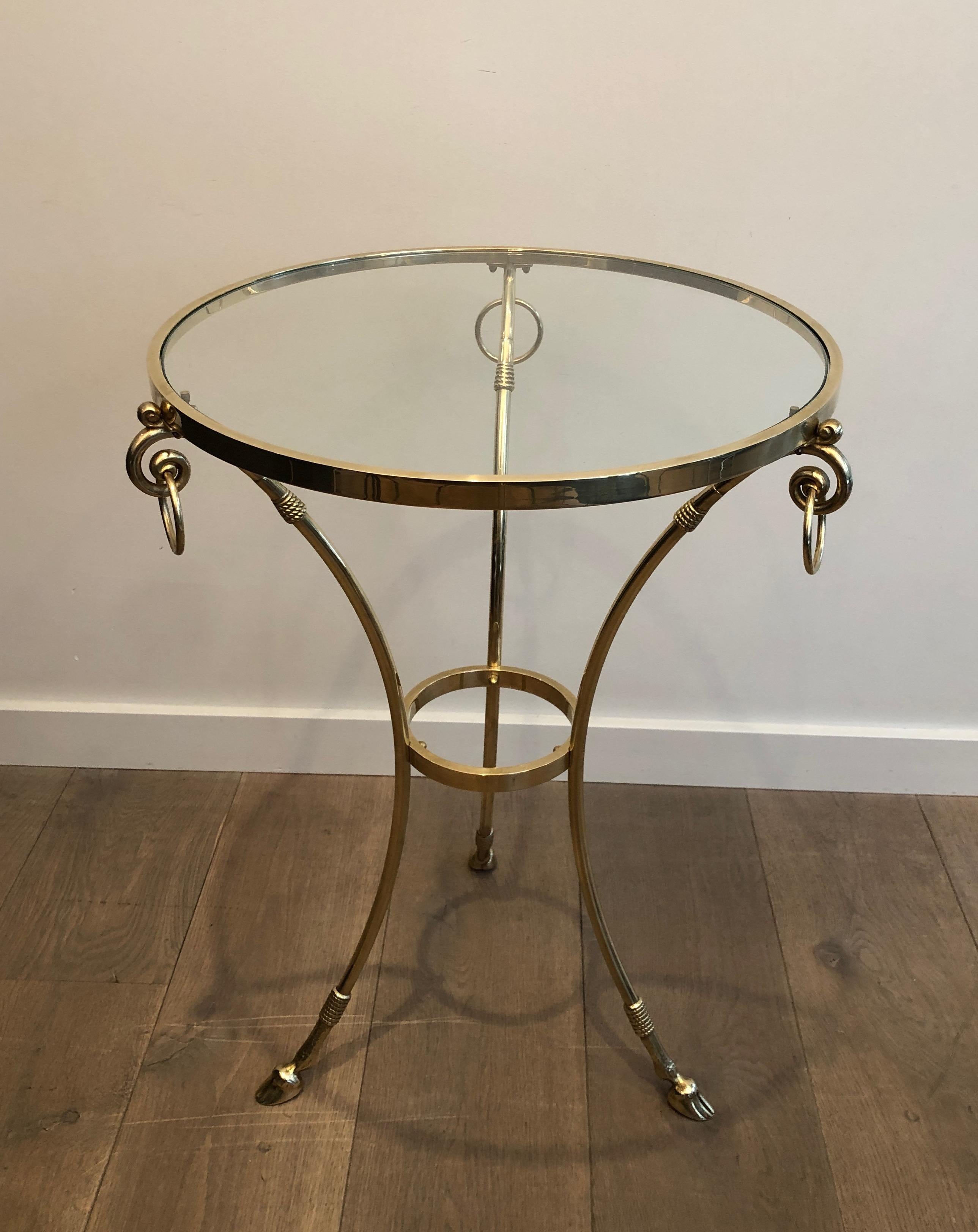 This Neoclassical style gueridon with doe feet and rings is made of brass with round glass shelf on top. This is a French work, circa 1970.
