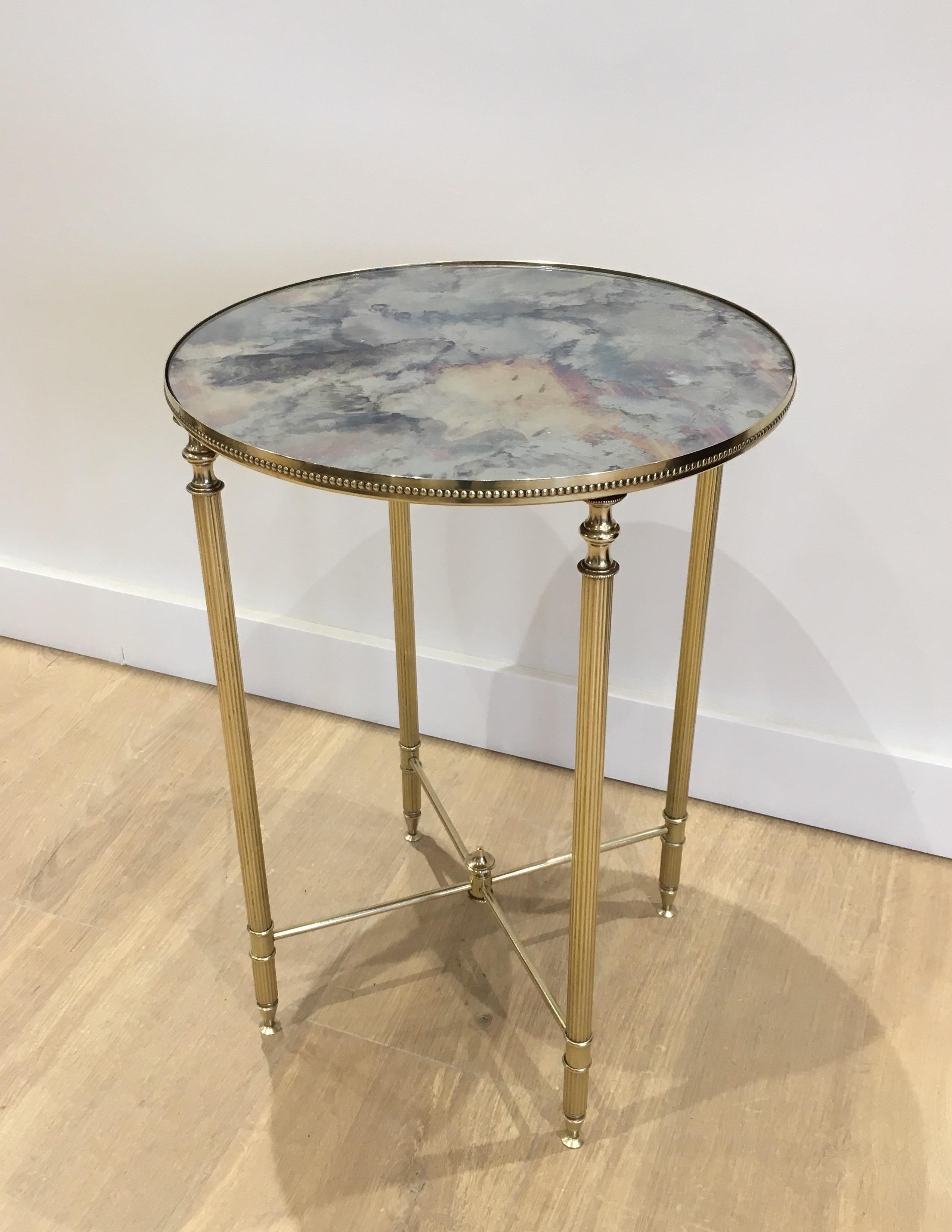 This neoclassical style round side table is made of brass with faux-antiques mirror top. This is a very nice work in the style of famous French designer Maison Jansen, circa 1940.
