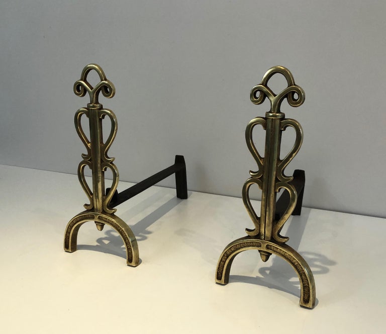 This very interesting pair of design andirons is made of brass and wrought iron. This is a french work in the style of Raymond Subes, circa 1940.