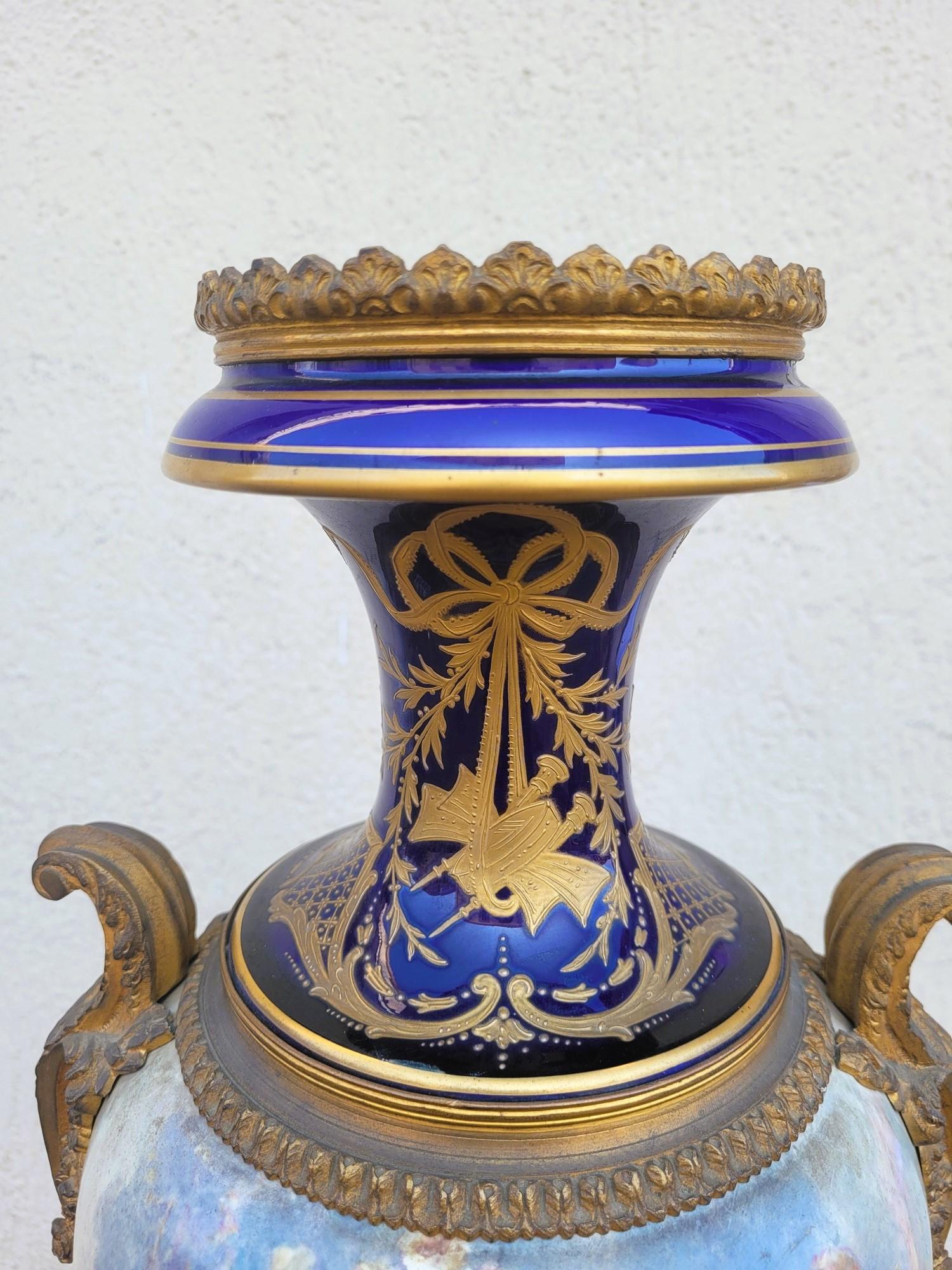 Grand vase en porcelaine dans le style de Sèvers, avec ornementation en bronze, monté sur une base rotative et décoré de figures féminines entourées de putti à l'avant et de vues de jardins et de paysages à l'arrière.
Décorations peintes sur fond