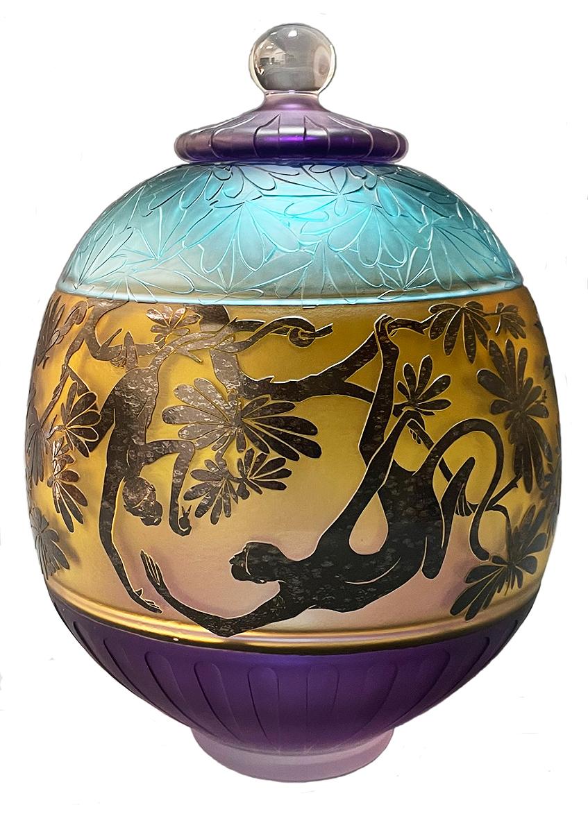 This cameo etched lidded jar by Gary Genetti is incalmo and overlay blown glass. The original artwork is drawn, hand cut then pressure etched through layers of color to create the imagery. The top, bottom sections and lid are deeply sandblast