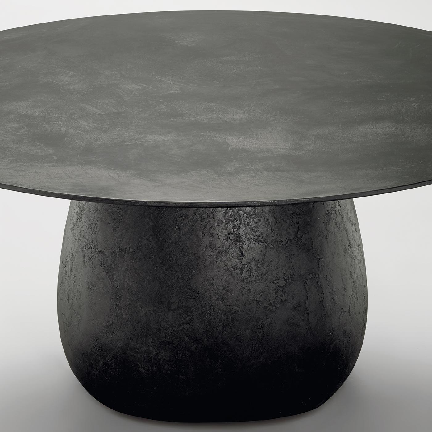 Dieser kühne und raffinierte Esstisch zeichnet sich durch eine skulpturale Silhouette aus, die sich aus zwei Elementen zusammensetzt: einem stabilen Unterbau aus Stahlbeinen, die von hartem Polyurethan umgeben sind, und einer runden Platte aus