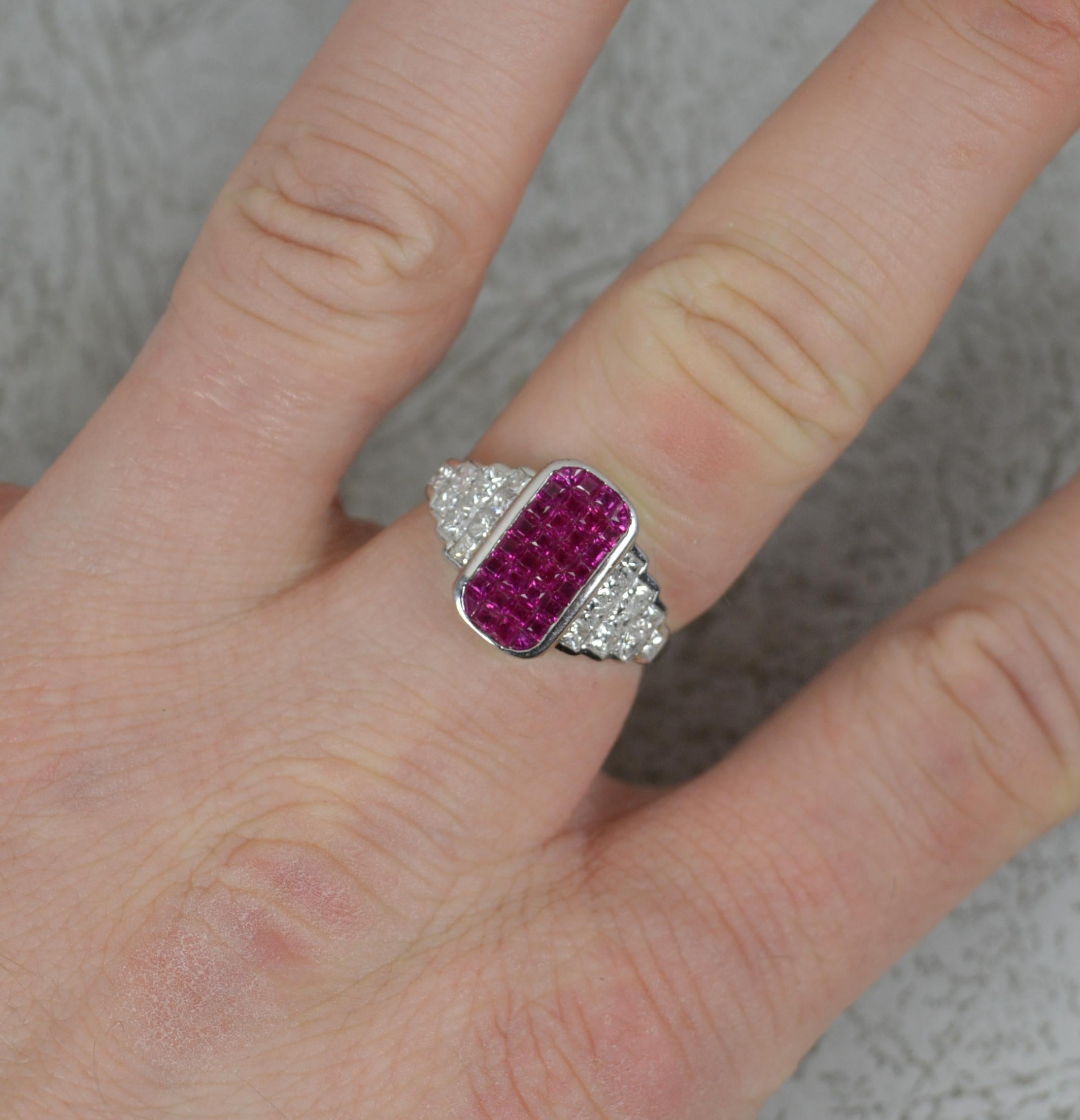 A highly unsual and striking ring.
Solid 18 carat white gold.
Designed an oval cluster of princess cut rubies to centre, 6.4mm x 12.3mm. To each side are ten princess cut diamonds to total 0.75cts approx Very white, clean and sparkly.
18mm x 13mm