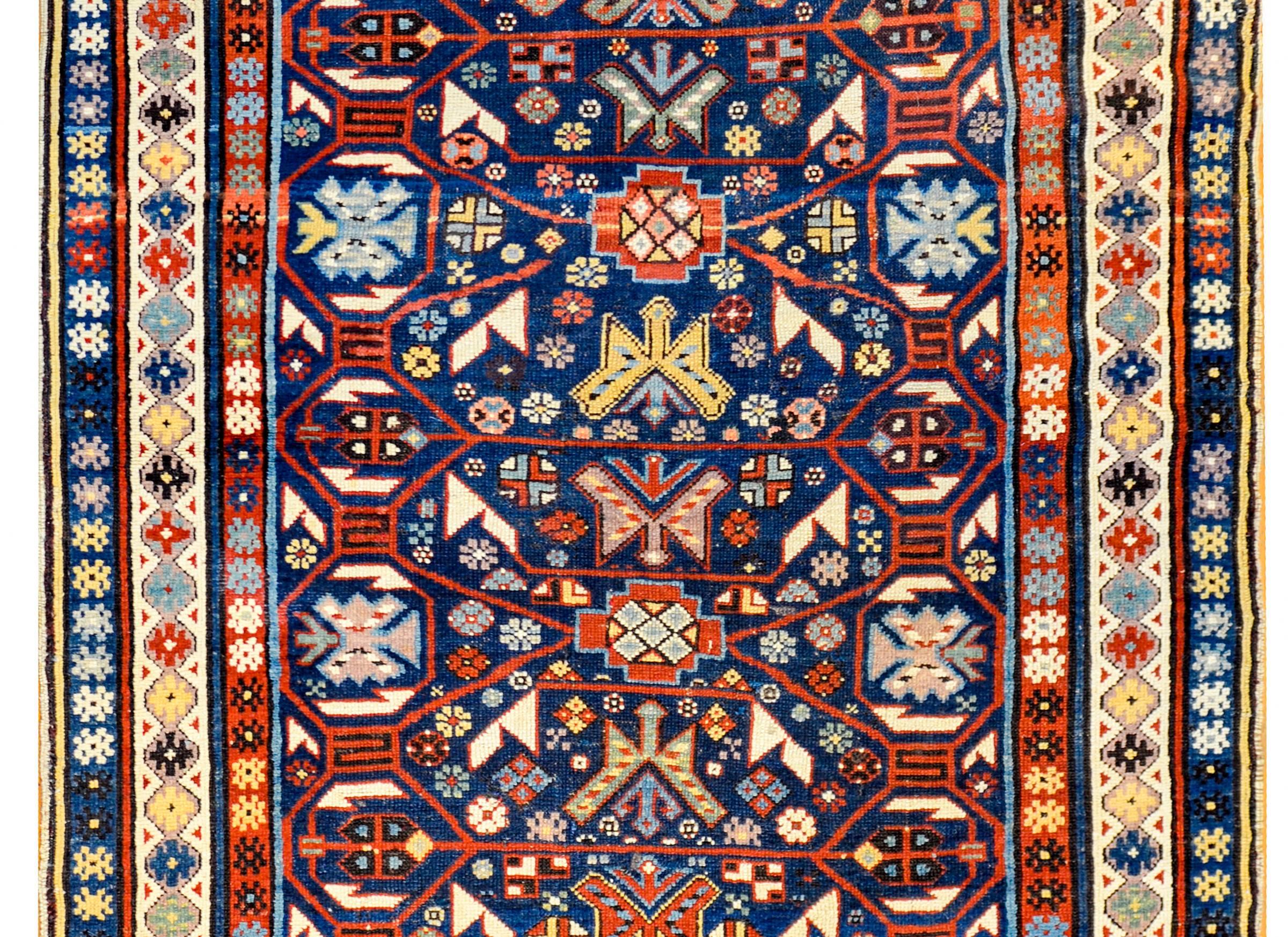 Un incroyable tapis Derbend datant de 1900 avec un motif floral stylisé multicolore densément tissé, avec un magnifique treillis cramoisi en dentelle recouvrant le fond indigo foncé. La bordure est magnifique, avec trois bandes différentes à motifs