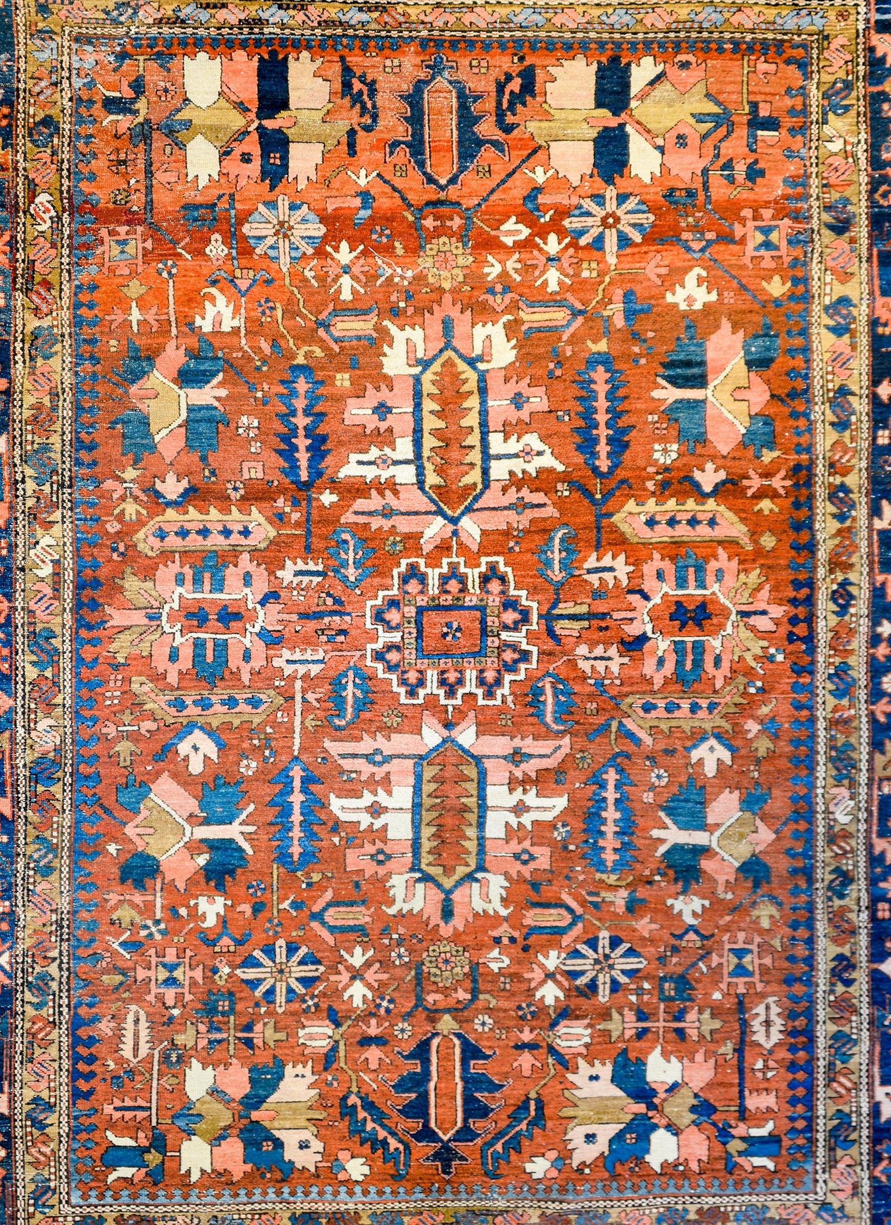 An incredible late 19th century Persian Bakhshyesh rug with a bold all-over tribal pattern of stylized flowers and leaves woven in crimson, light and dark indigo, pink, and white vegetable dyed wool, on a brilliant crimson background. The border is