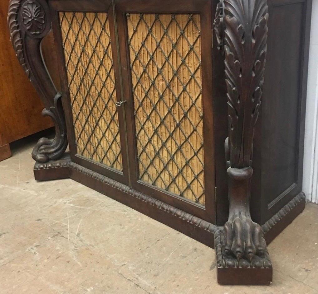 Incredible 19th century English Regency marble top console. Slab marble is fixed to the top of the console. Elegantly carved frieze and knees over paw feet, all resting on a plinth base with gadrooning. Two grille work cabinet doors open to two