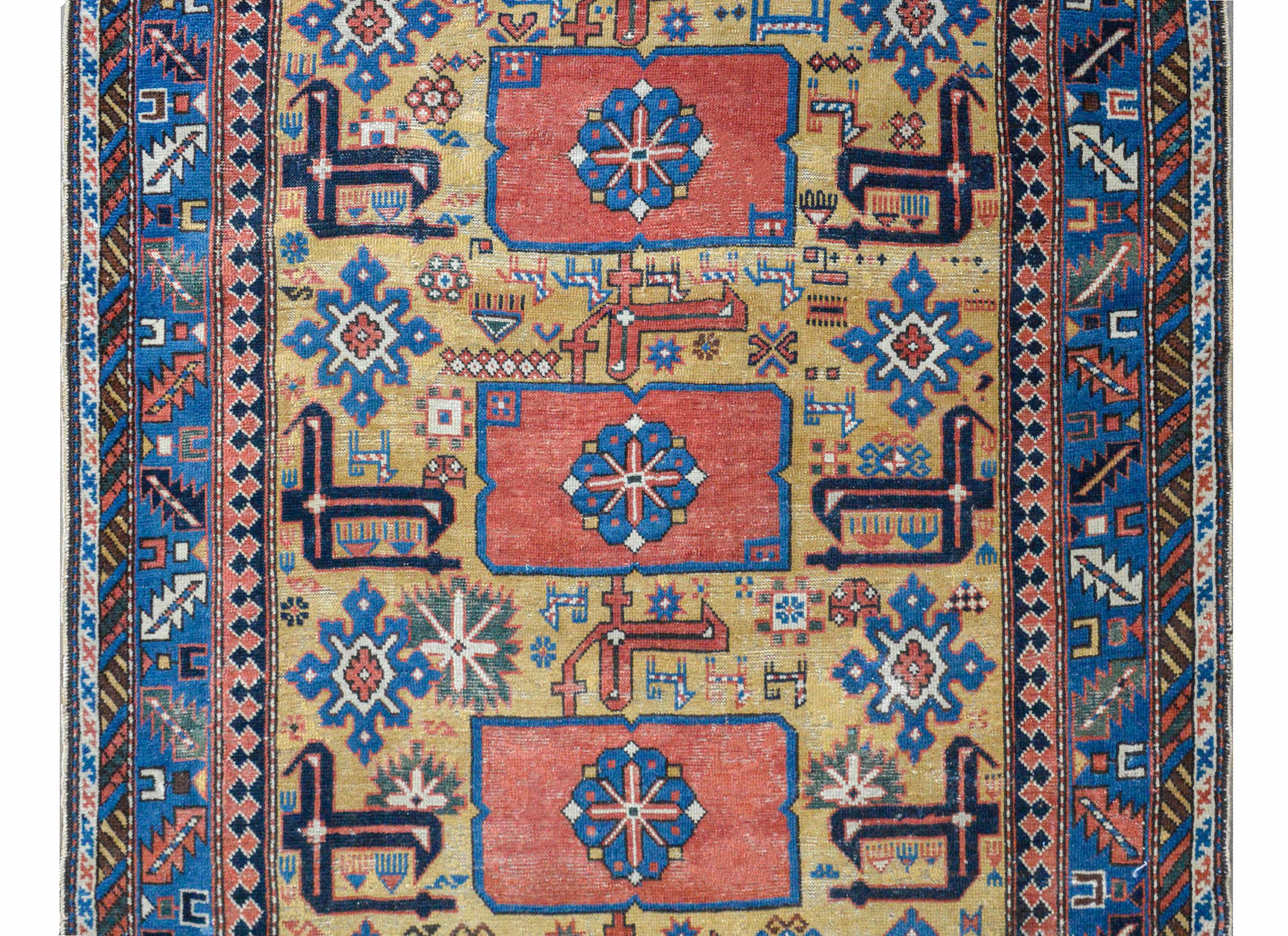 An incredible early 20th century Qaraqashli rug with boldly stylized floral medallions against gold field of more stylized flowers all woven in light and dark indigo, coral, and white, and surrounded by a wonderful wide border with more stylized