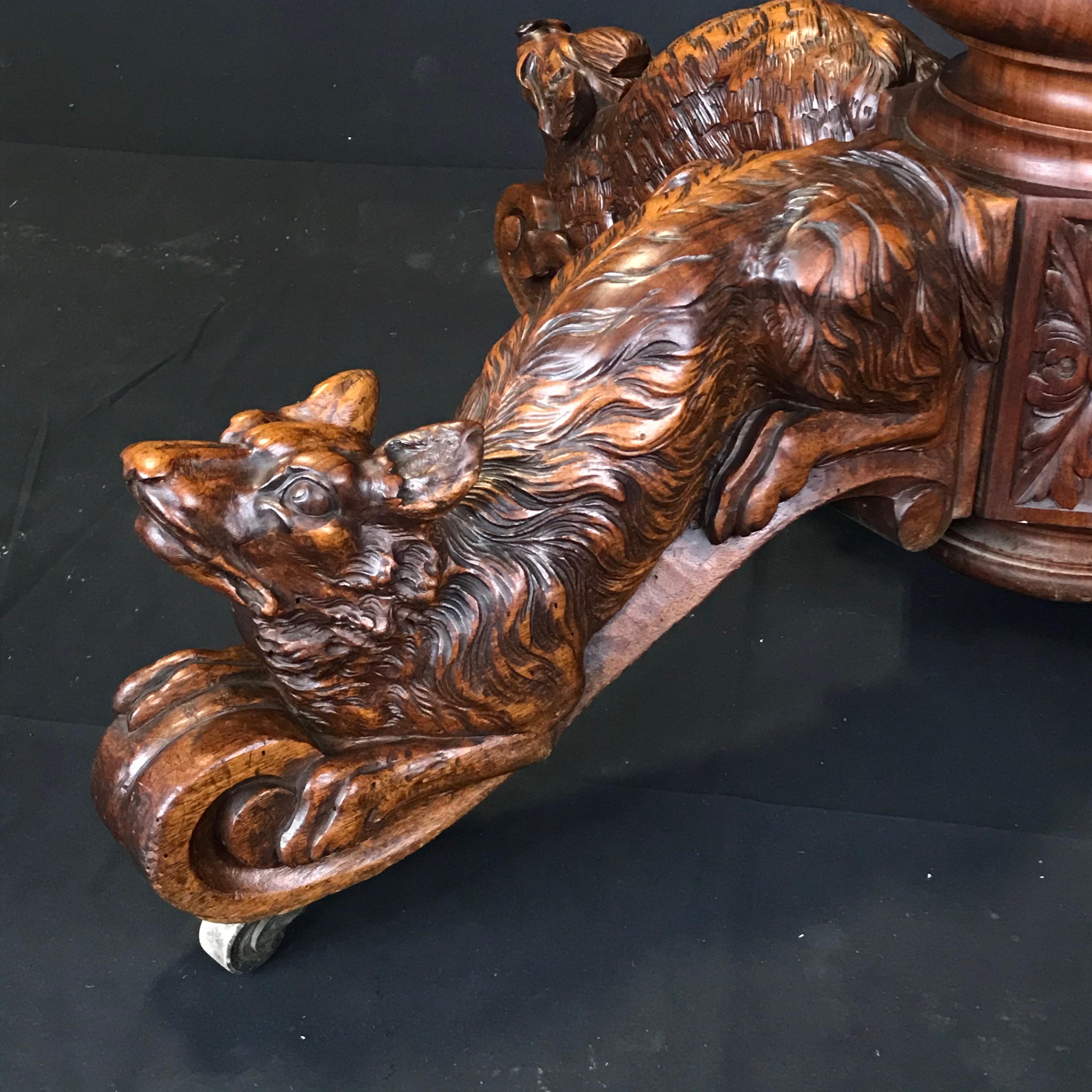 A strikingly beautiful French antique walnut hunting table having intricately detailed figures of a hunting retriever dog, boar, fox and deer on its single pedestal base. Typical of the Renaissance Revival style produced in France in the 19th
