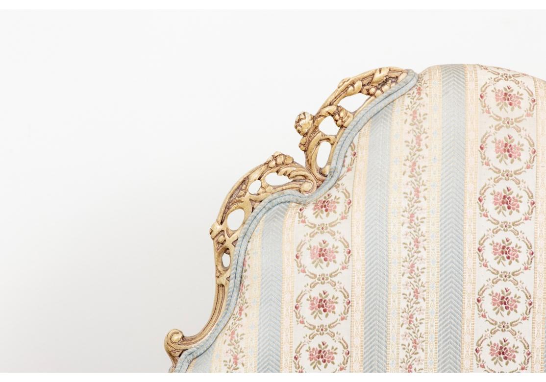 An amazing and dramatic pair of creme paint frame armchairs with delicately carved and Intricate frames and top trim. Custom upholstered in a celadon striped silk-type fabric with needlepoint style floral accents. Very well made with spring seats,