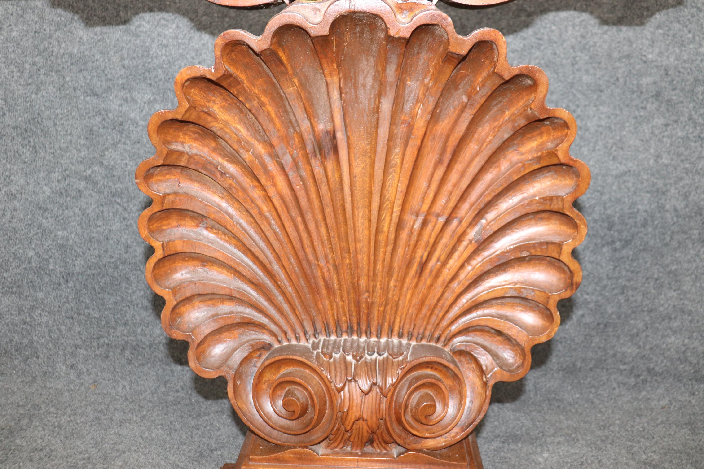 This is a beautiful carved walnut Italian-made console table. The table features a clear glass top above a gorgeous, large shell motif. The table is in good condition with minor and shown dings, losses and signs of age and use. The table dates to