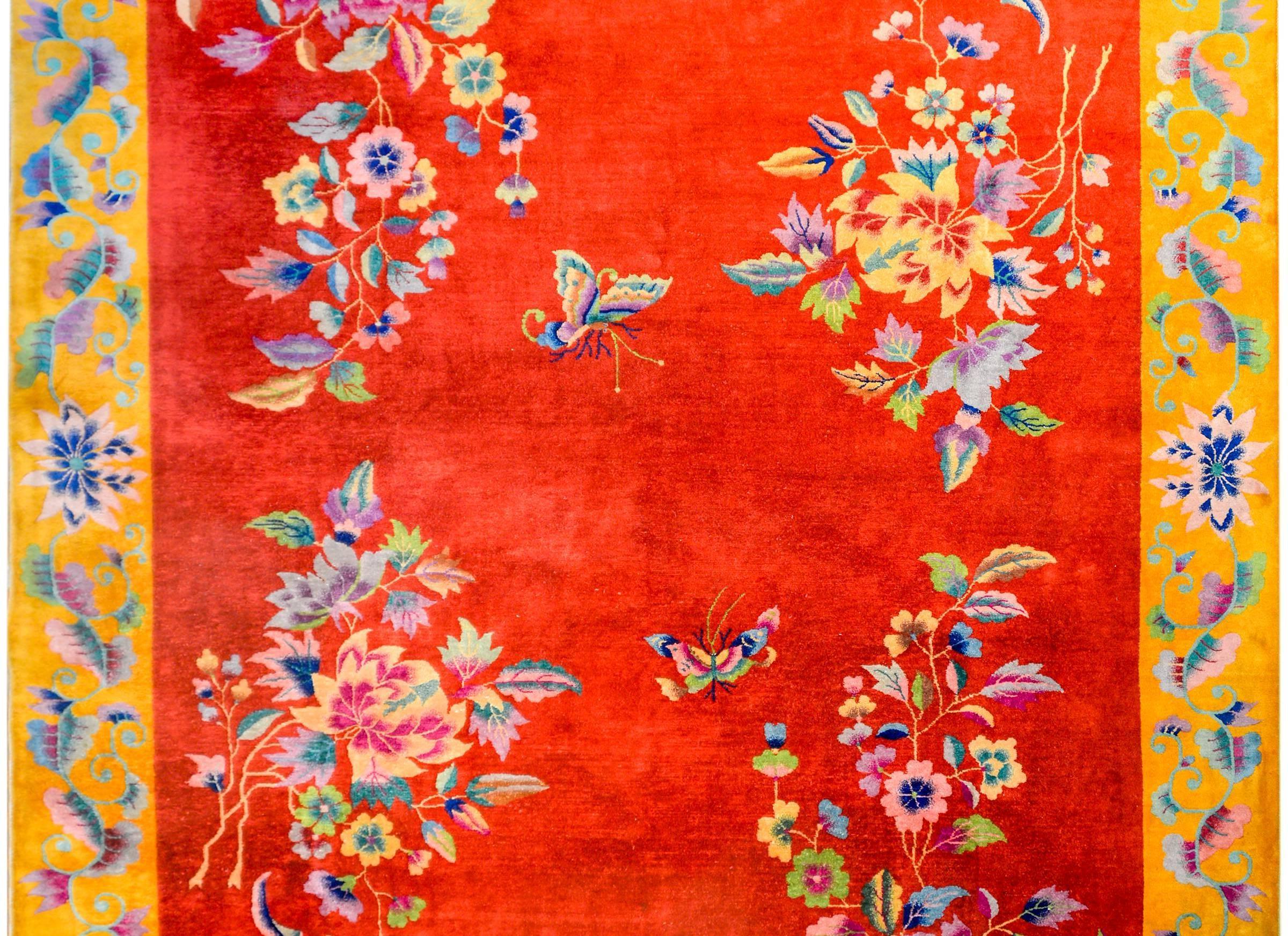 A brilliant early 20th century, Chinese Art Deco rug with an asymmetrical floral pattern containing multicolored peonies and chrysantemum in opposite corners, and butterflies, on a bold crimson background. The border is wide, with a complimentary